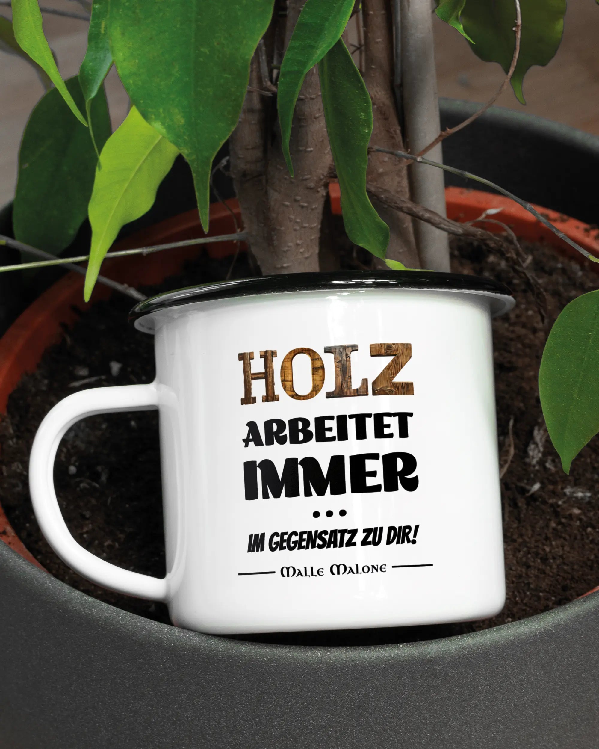 Aufnahme der linken Seite der beidseitig bedruckten Emailletasse von Maondo mit dem Design Holzarbeit in der Farbe White-Black in einem Blumentopf