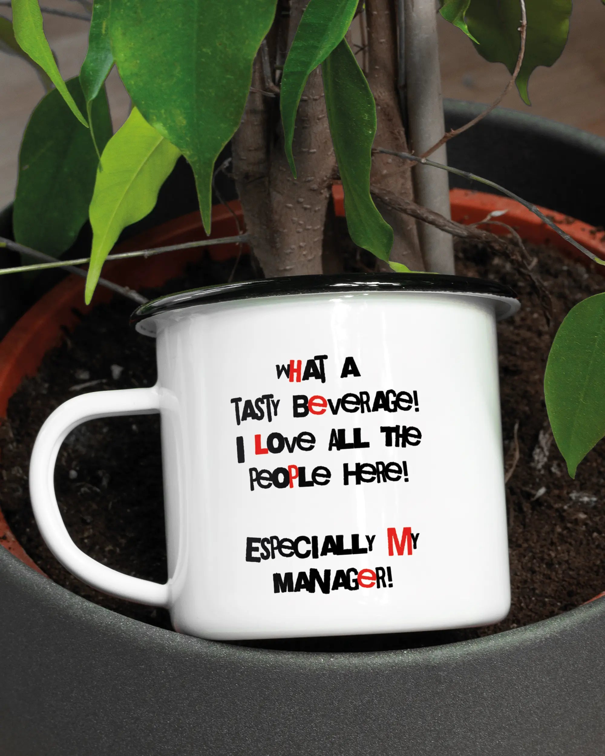 Aufnahme der linken Seite der beidseitig bedruckten Emailletasse von Maondo mit dem Design Help me in der Farbe White-Black in einem Blumentopf