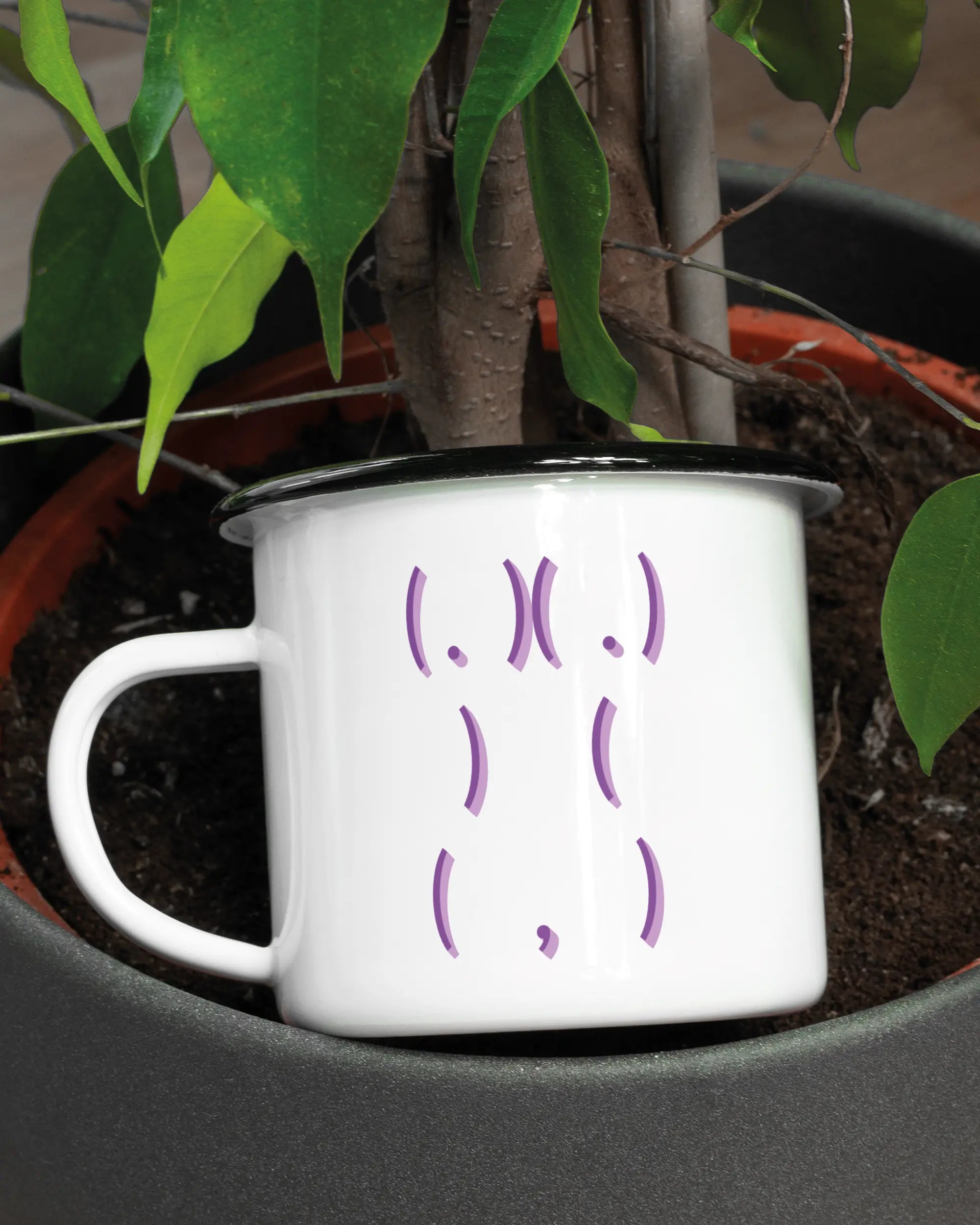 Aufnahme der linken Seite der beidseitig bedruckten Emailletasse von Maondo mit dem Design Body Language in der Farbe White-Black in einem Blumentopf