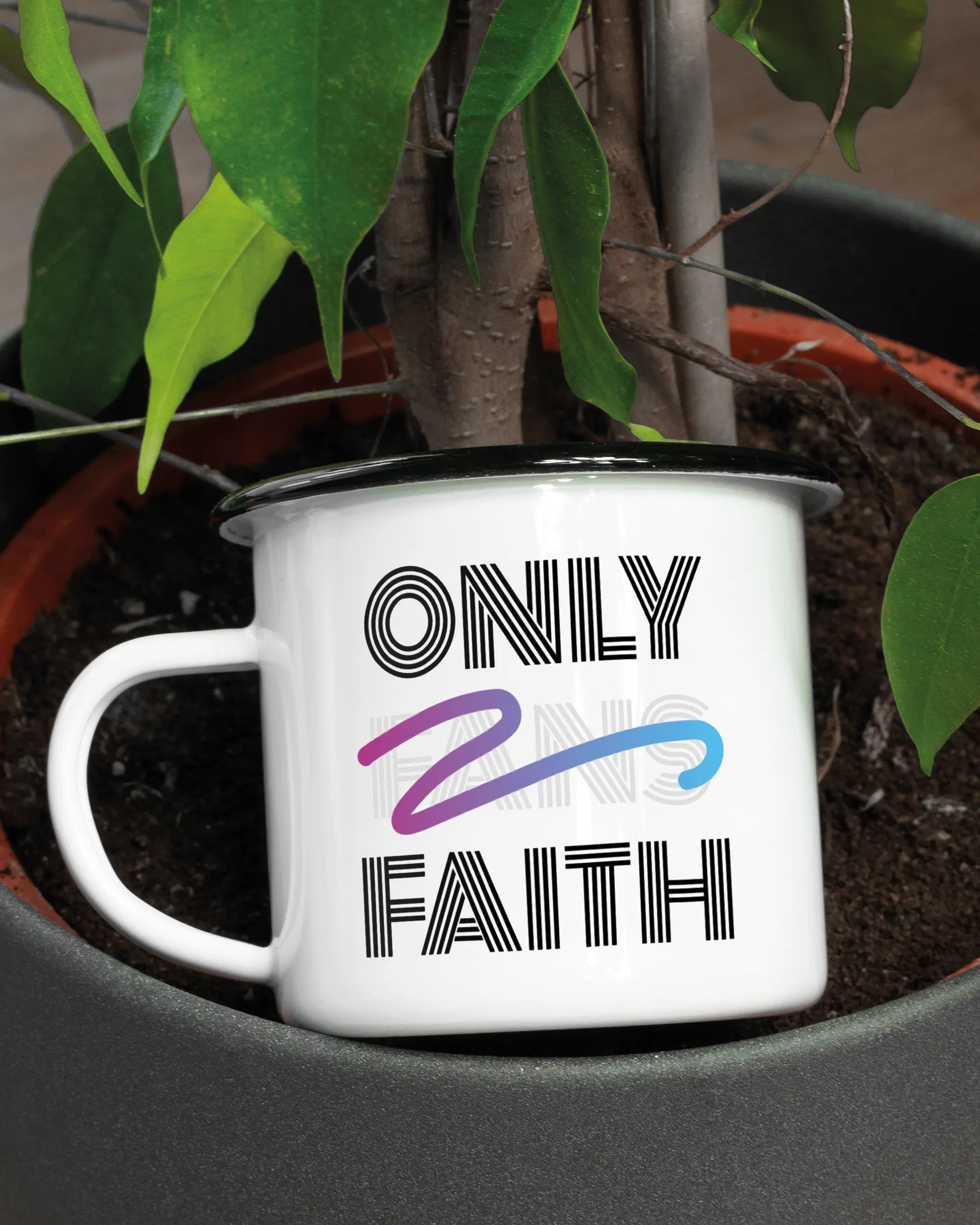 Aufnahme der linken Seite der beidseitig bedruckten Emailletasse von Maondo mit dem Design Only Faith in der Farbe White-Black in einem Blumentopf