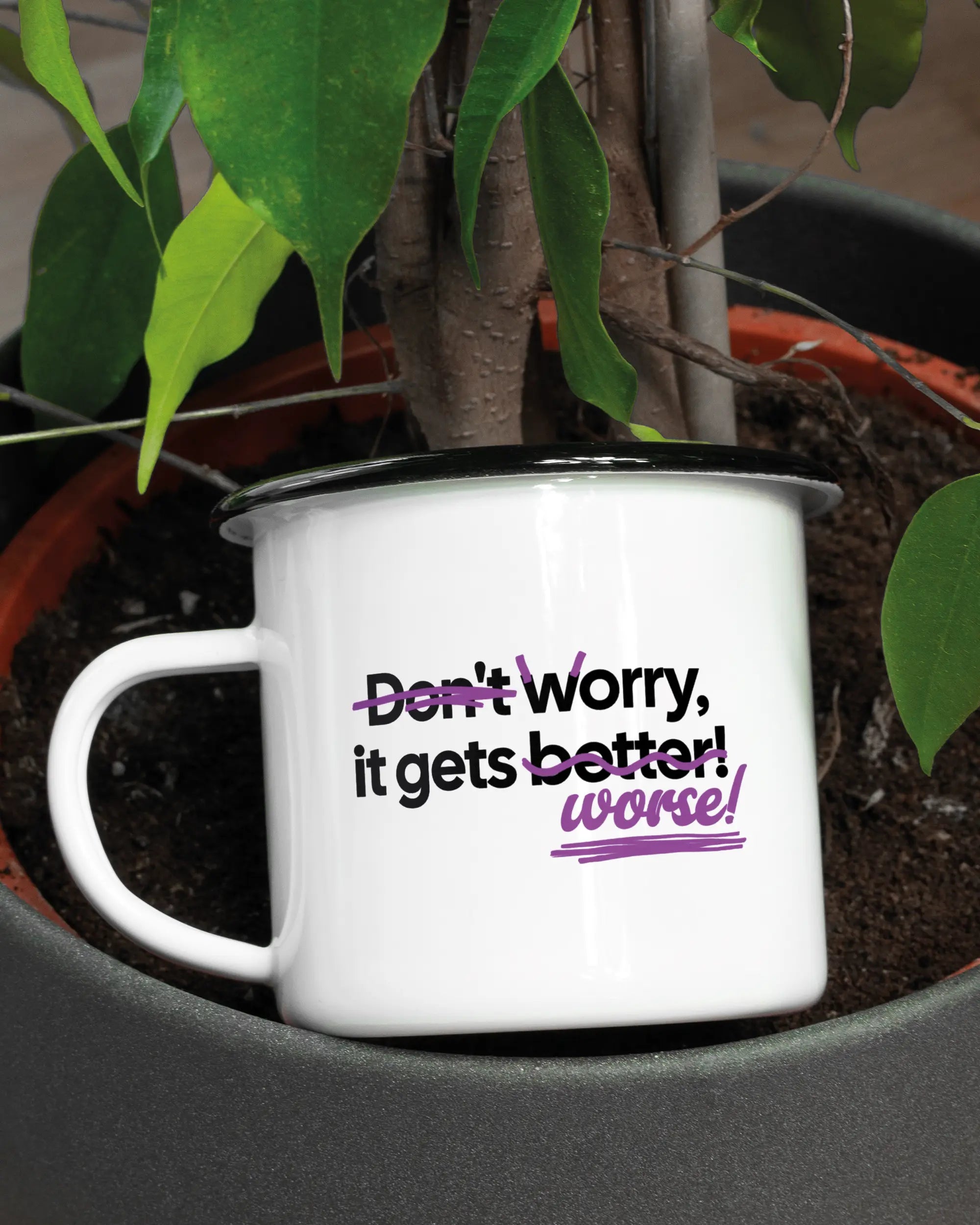 Aufnahme der linken Seite der beidseitig bedruckten Emailletasse von Maondo mit dem Design Worry Worse in der Farbe White-Black in einem Blumentopf