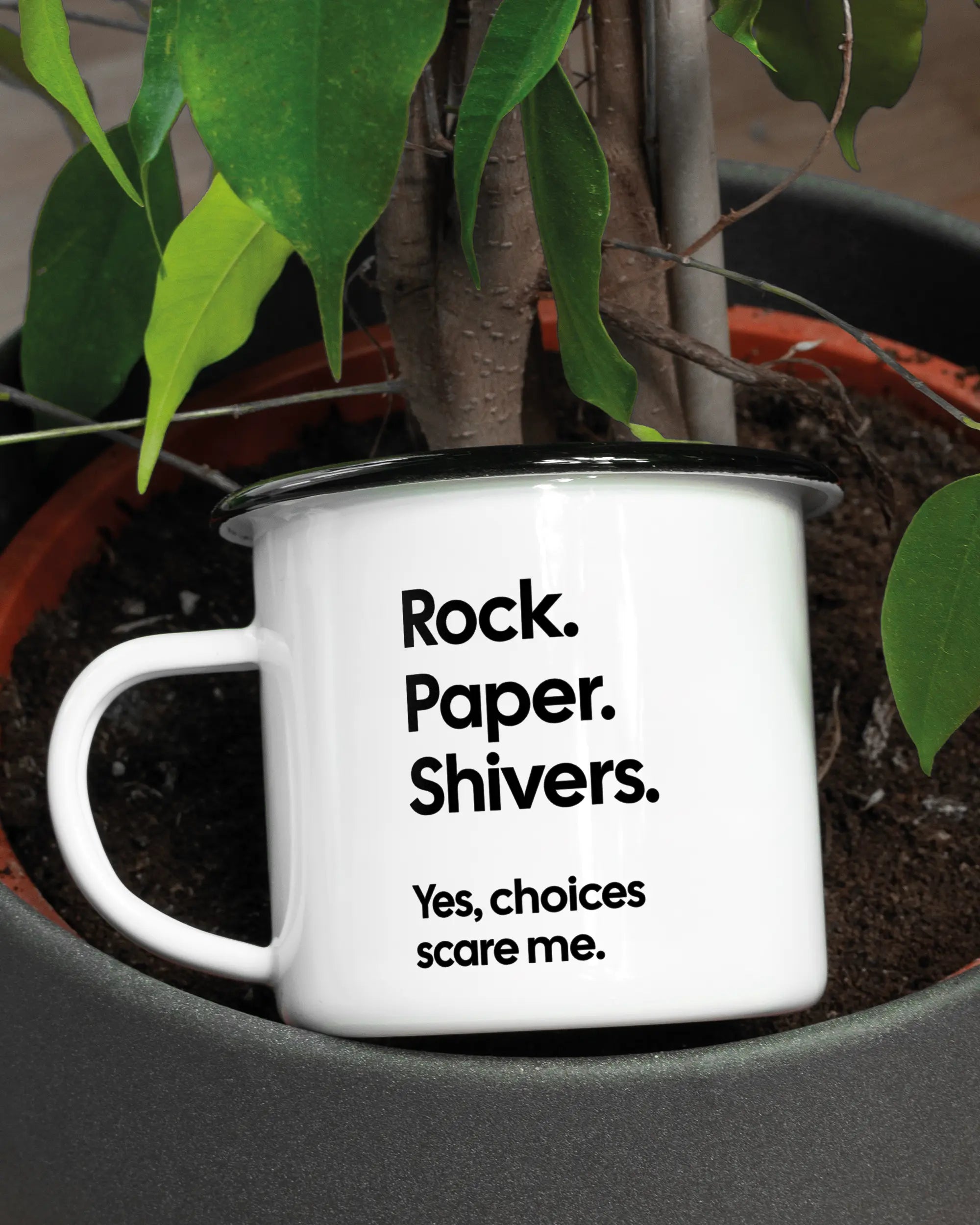 Aufnahme der linken Seite der beidseitig bedruckten Emailletasse von Maondo mit dem Design Rock Paper Shivers in der Farbe White-Black in einem Blumentopf