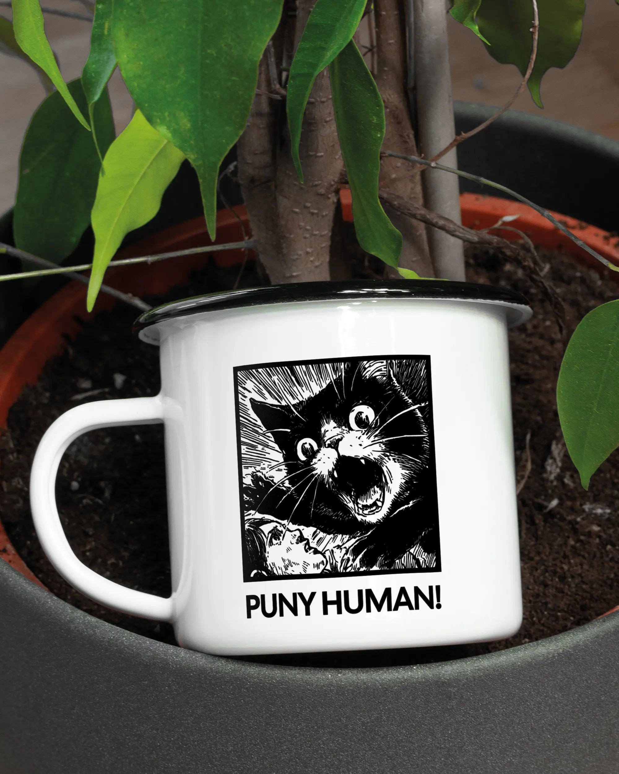 Aufnahme der linken Seite der beidseitig bedruckten Emailletasse von Maondo mit dem Design Puny Human in der Farbe White-Black in einem Blumentopf