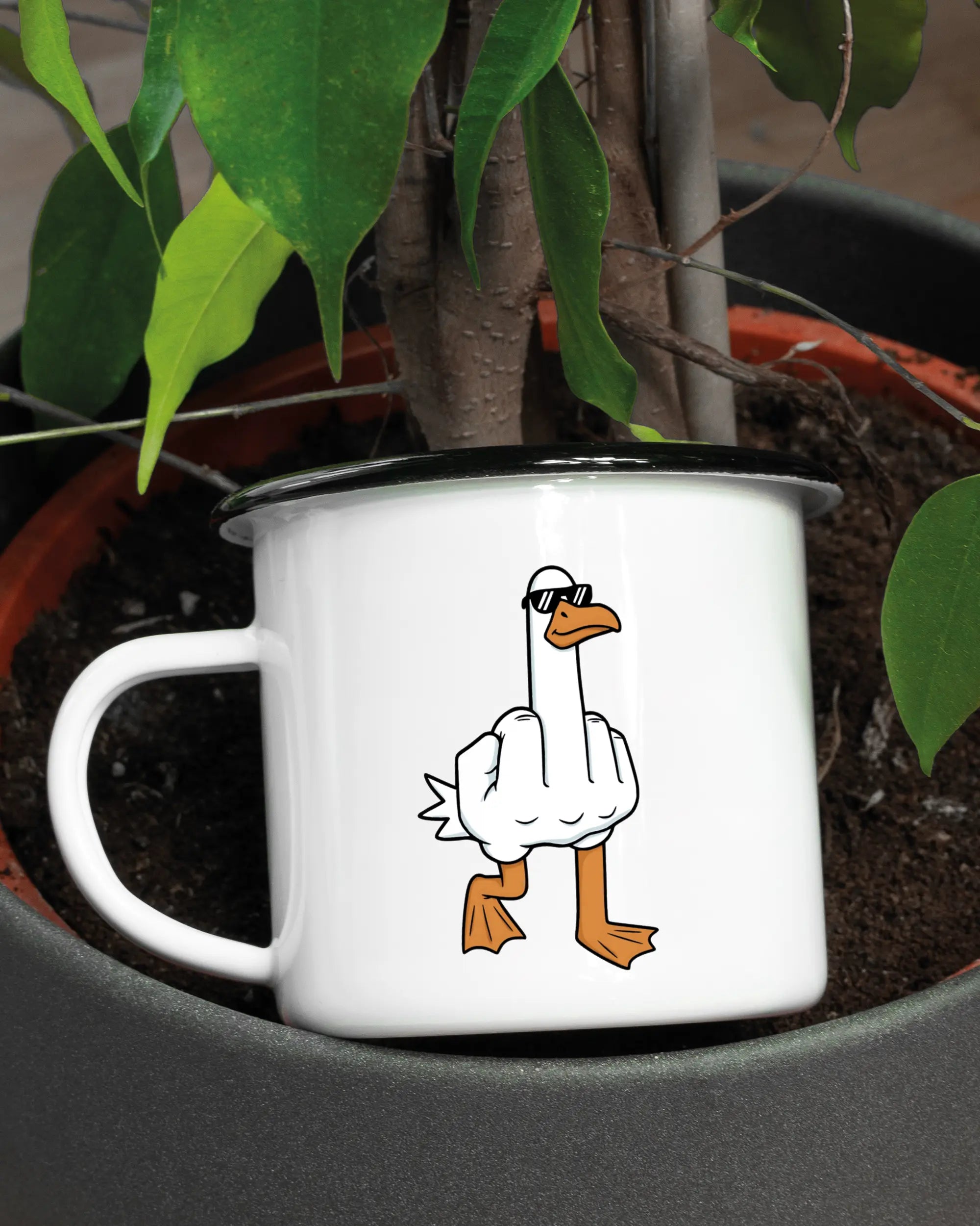 Aufnahme der linken Seite der beidseitig bedruckten Emailletasse von Maondo mit dem Design I give a duck in der Farbe White-Black in einem Blumentopf