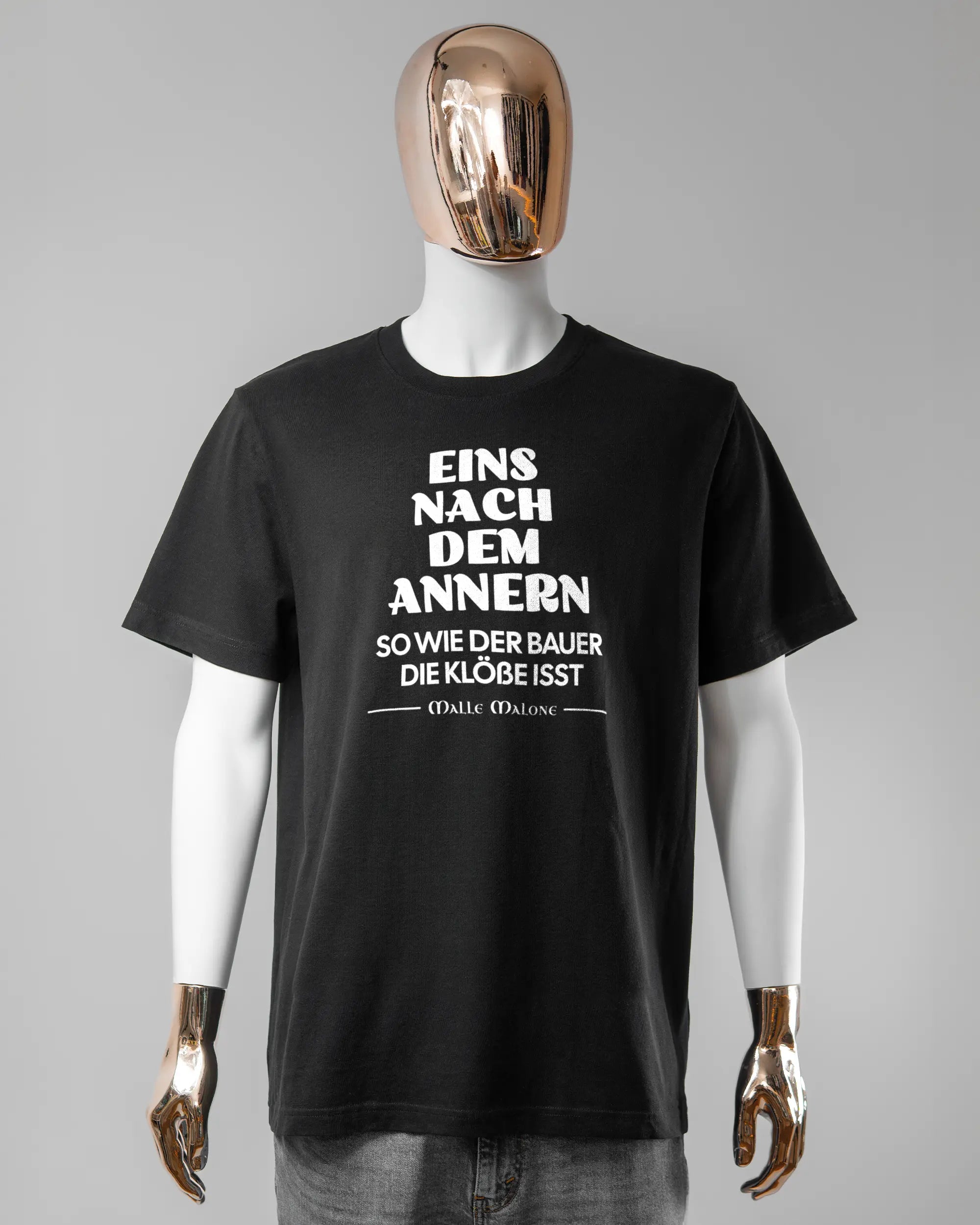 Vorderseite des Organic Unisex T-Shirt Relaxed von Maondo mit dem Design Eins nach dem Annern in der Farbe Black und in der Größe L getragen von einer maskulinen Puppe