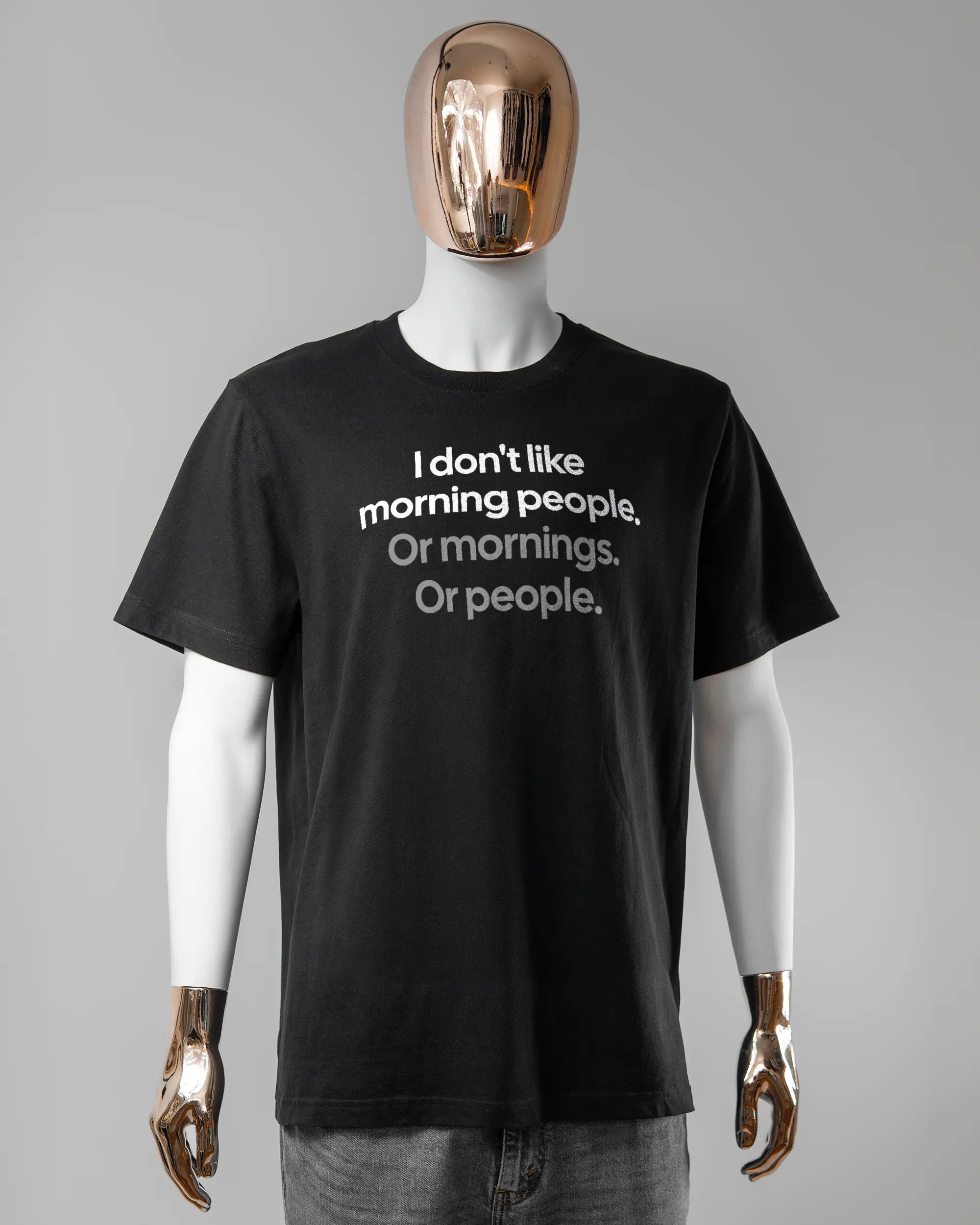 Vorderseite des Organic Unisex T-Shirt Relaxed von Maondo mit dem Design Morning Person in der Farbe Black und in der Größe L getragen von einer maskulinen Puppe