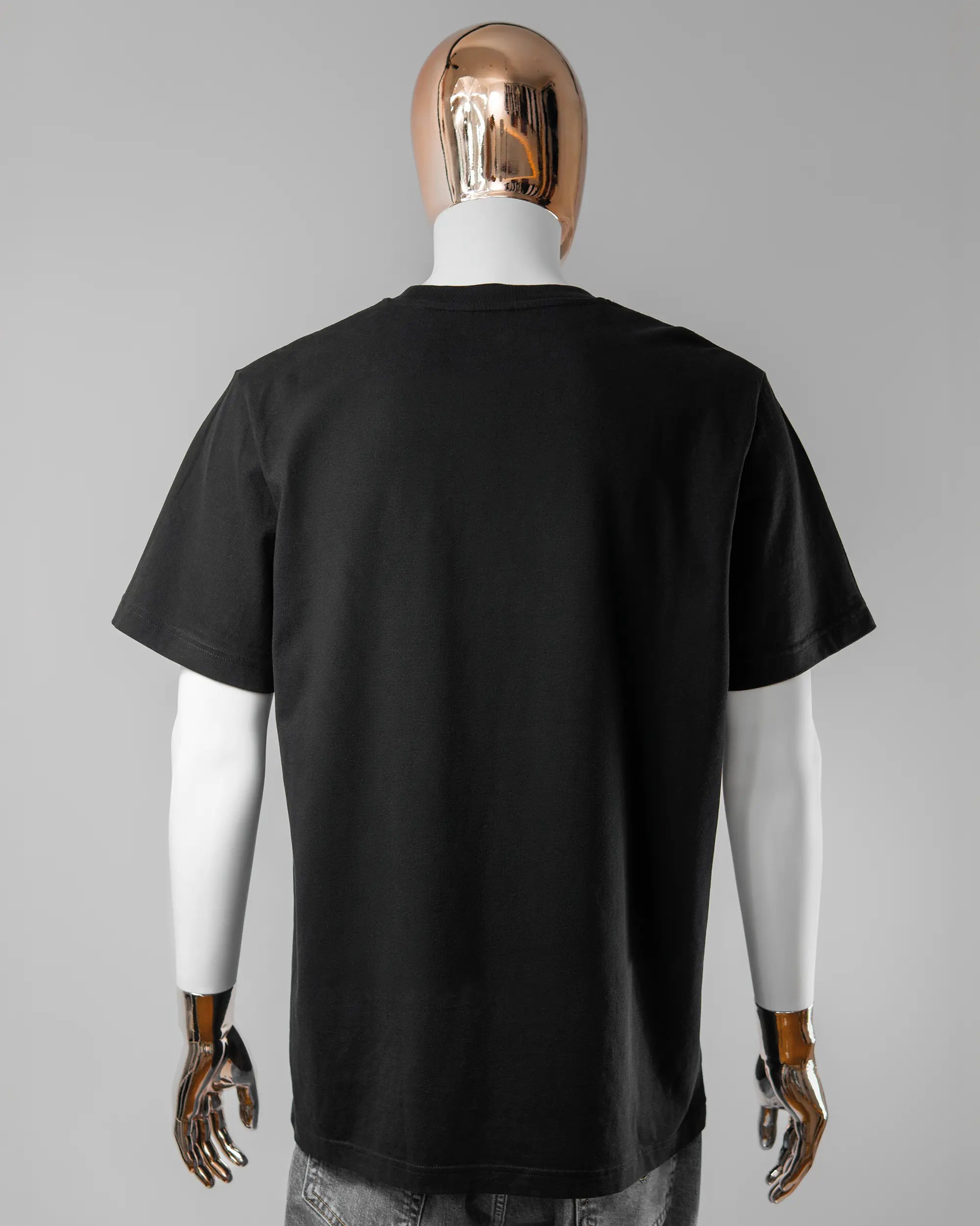 Rückseite des Organic Unisex T-Shirt Relaxed von Maondo ohne Motiv in der Farbe Black und in der Größe L getragen von einer maskulinen Puppe