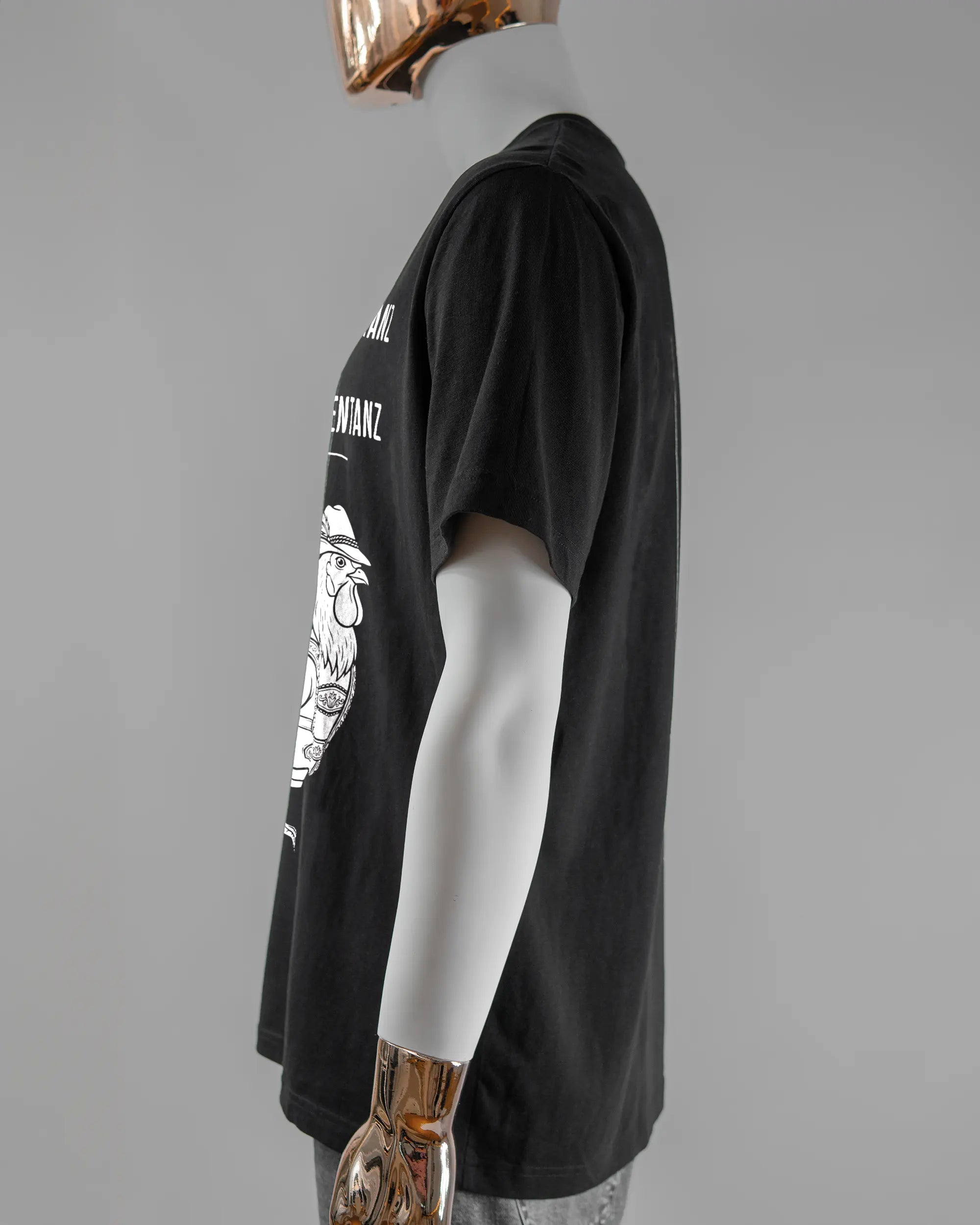 Seitenansicht des Organic Unisex T-Shirt Relaxed von Maondo mit dem Design Trachtentanz vorne in der Farbe Black und in der Größe L getragen von einer maskulinen Puppe