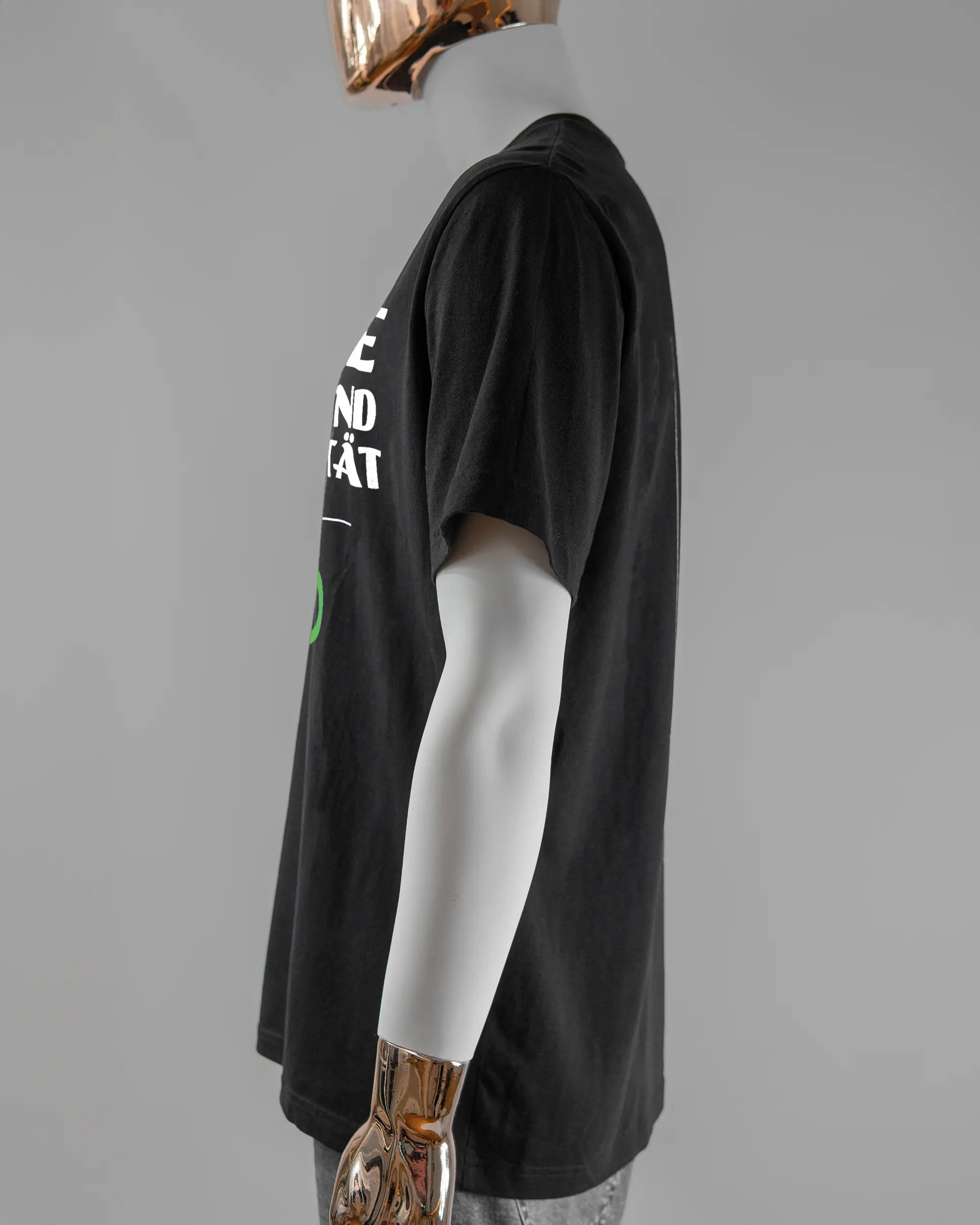 Seitenansicht des Organic Unisex T-Shirt Relaxed von Maondo mit dem Design Keine Eile vorne in der Farbe Black und in der Größe L getragen von einer maskulinen Puppe