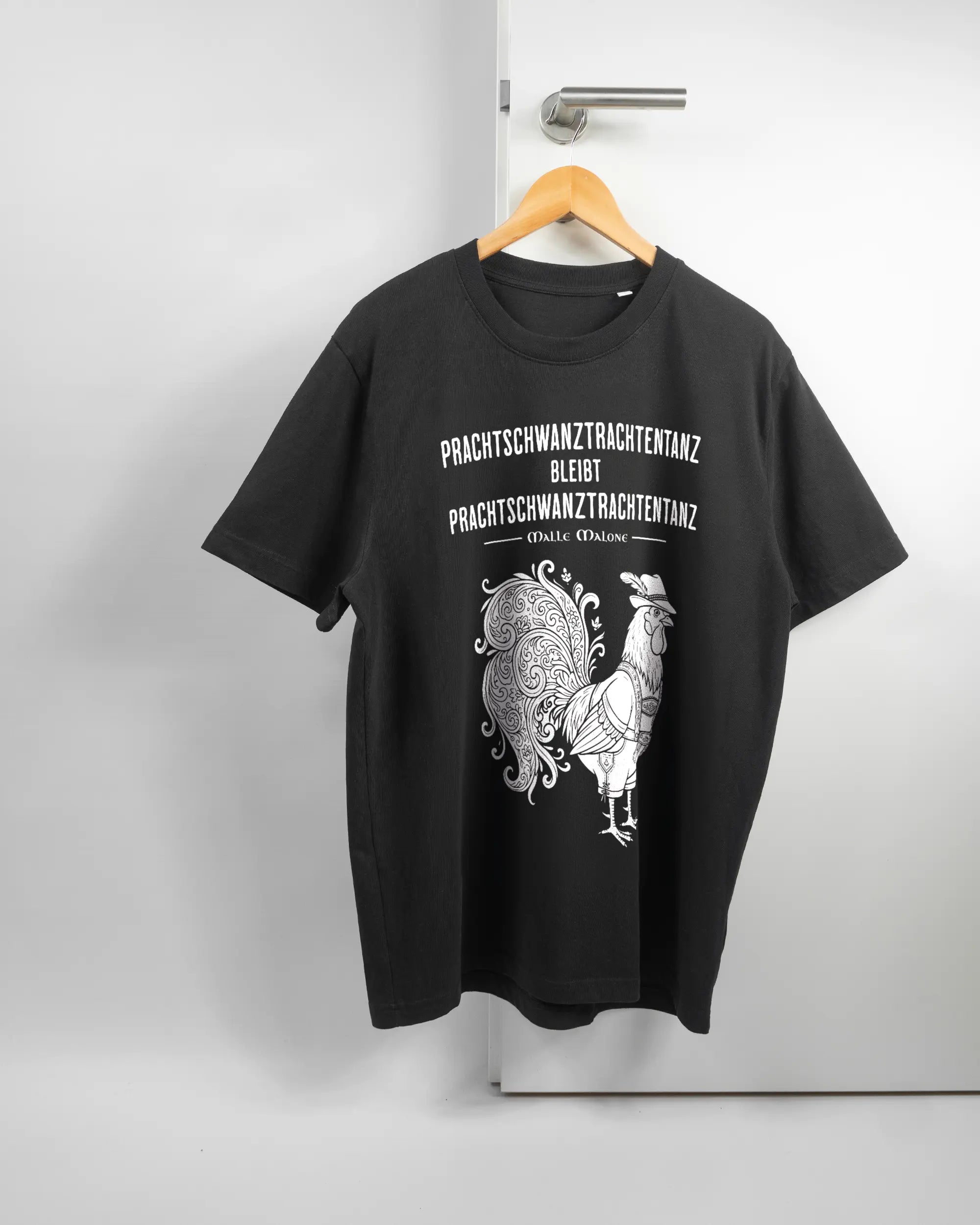 Vorderseite des Organic Unisex T-Shirt Relaxed von Maondo mit dem Design Trachtentanz in der Farbe Black und in der Größe L auf einem Bügel an der Türklinke aufgehängt