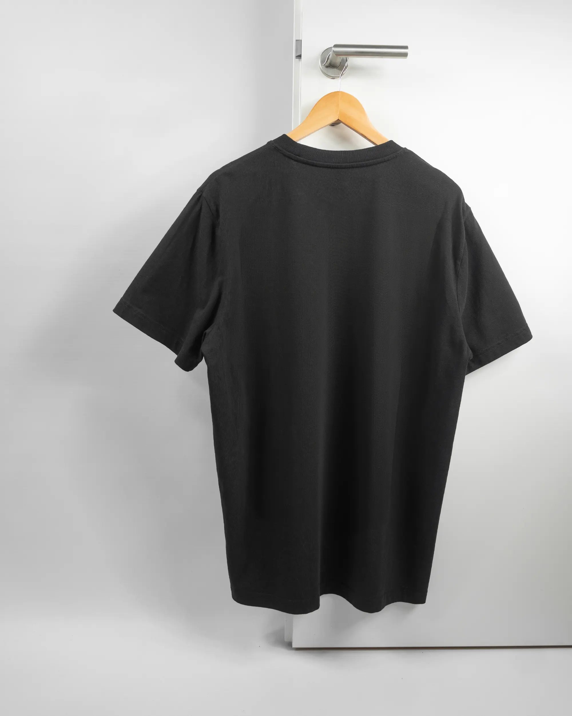 Rückseite des Organic Unisex T-Shirt Relaxed von Maondo ohne Motiv in der Farbe Black und in der Größe L auf einem Bügel an der Türklinke aufgehängt