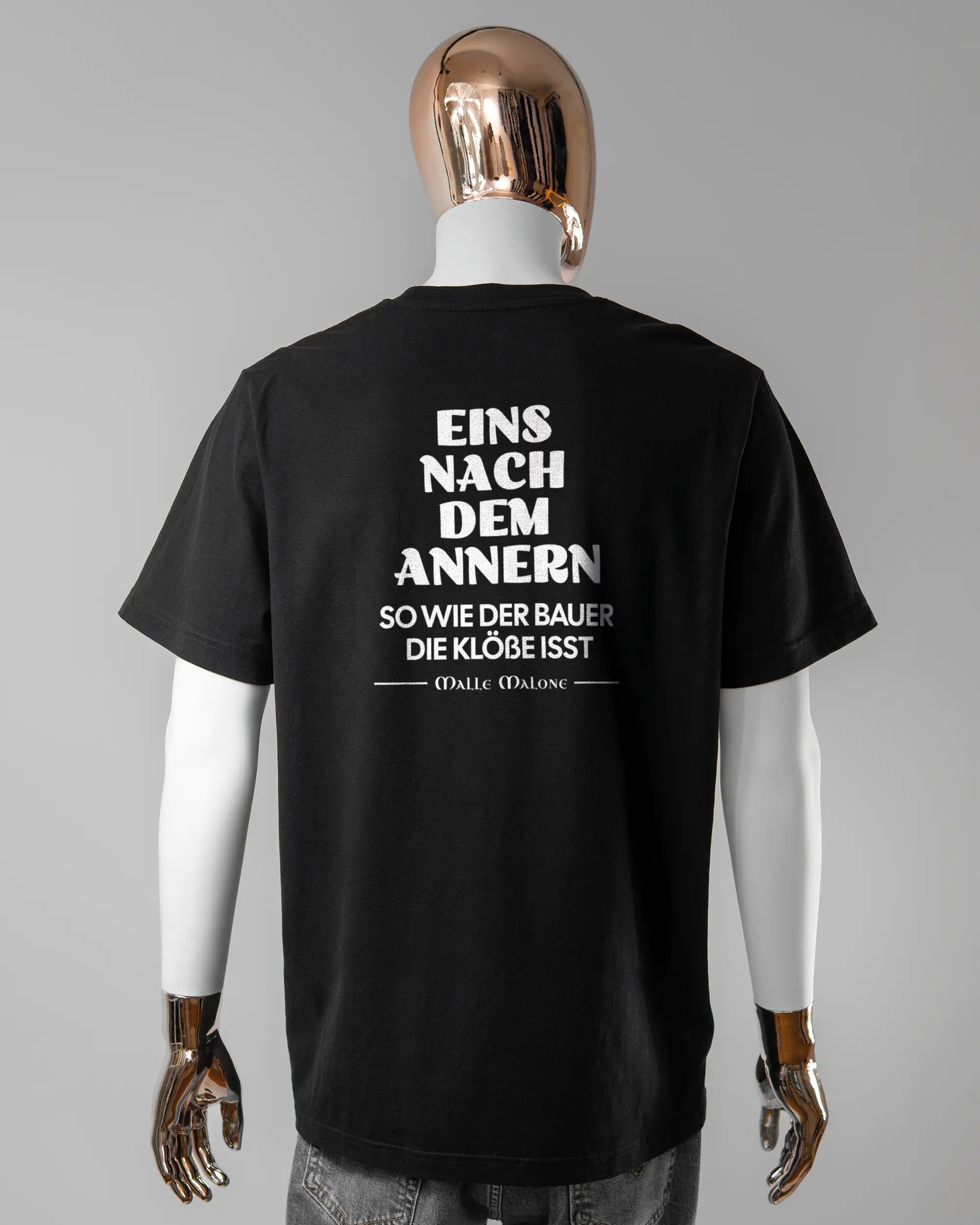 Rückseite des Organic Unisex T-Shirt Relaxed von Maondo mit dem Design Eins nach dem Annern in der Farbe Black und in der Größe L getragen von einer maskulinen Puppe