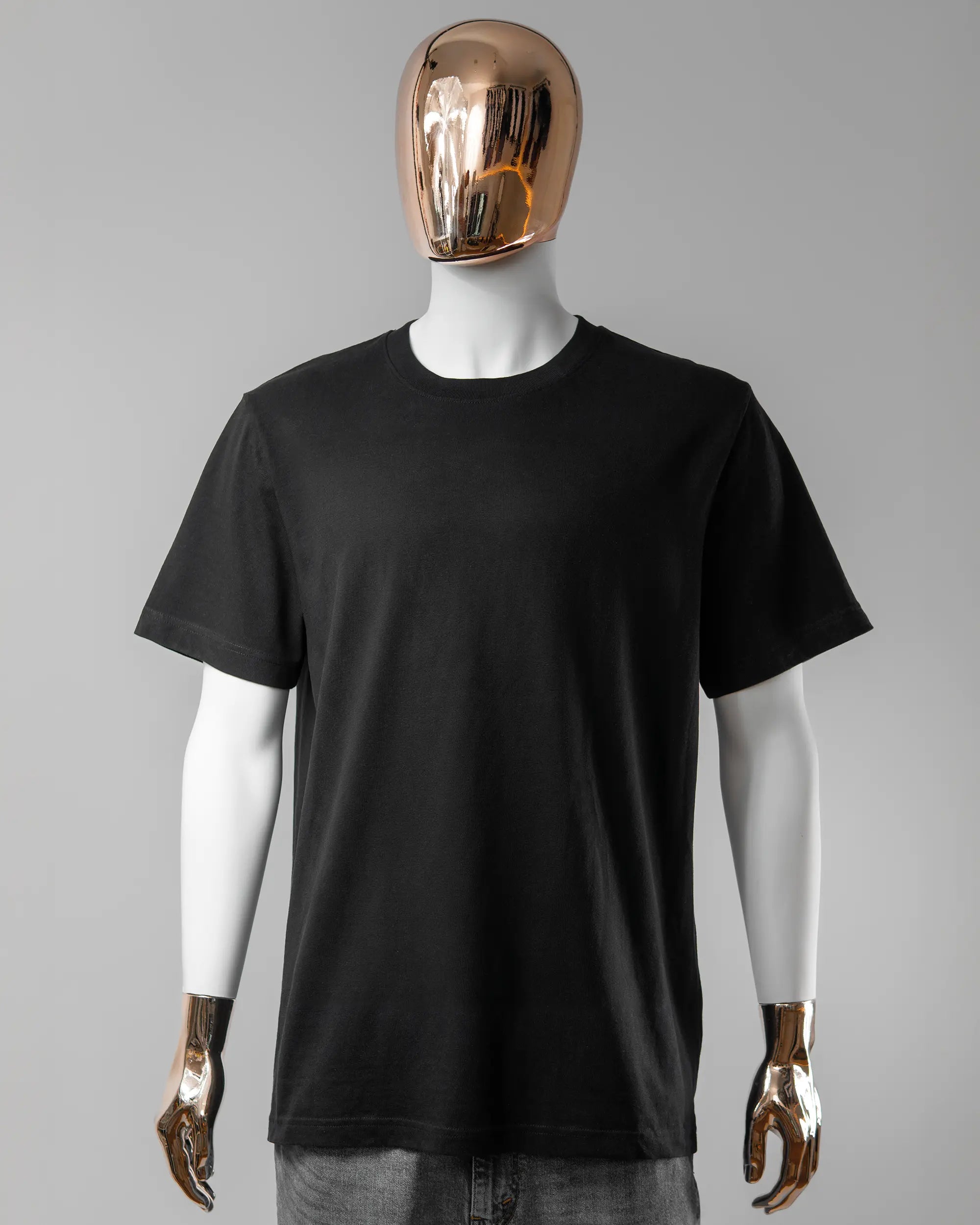 Vorderseite des Organic Unisex T-Shirt Relaxed von Maondo ohne Motiv in der Farbe Black und in der Größe L getragen von einer maskulinen Puppe