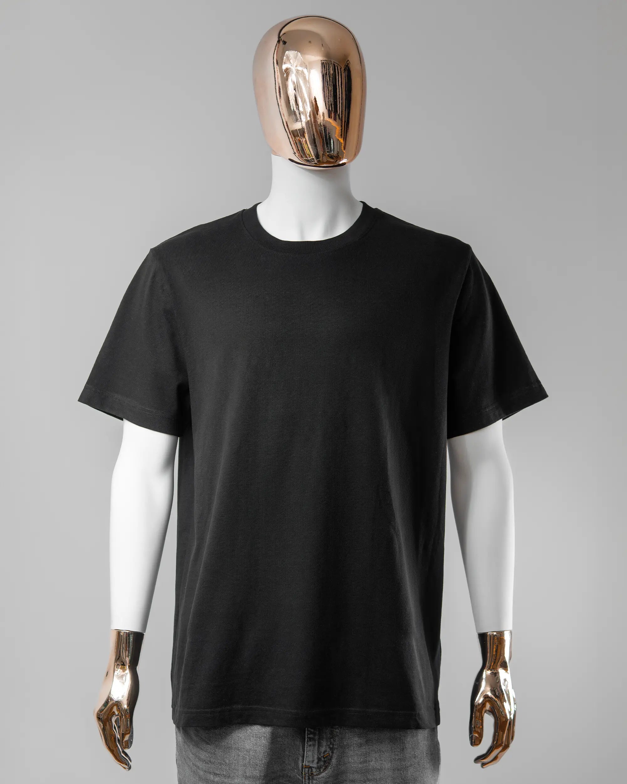 Vorderseite des Organic Unisex T-Shirt Relaxed von Maondo ohne Motiv in der Farbe Black und in der Größe L getragen von einer maskulinen Puppe