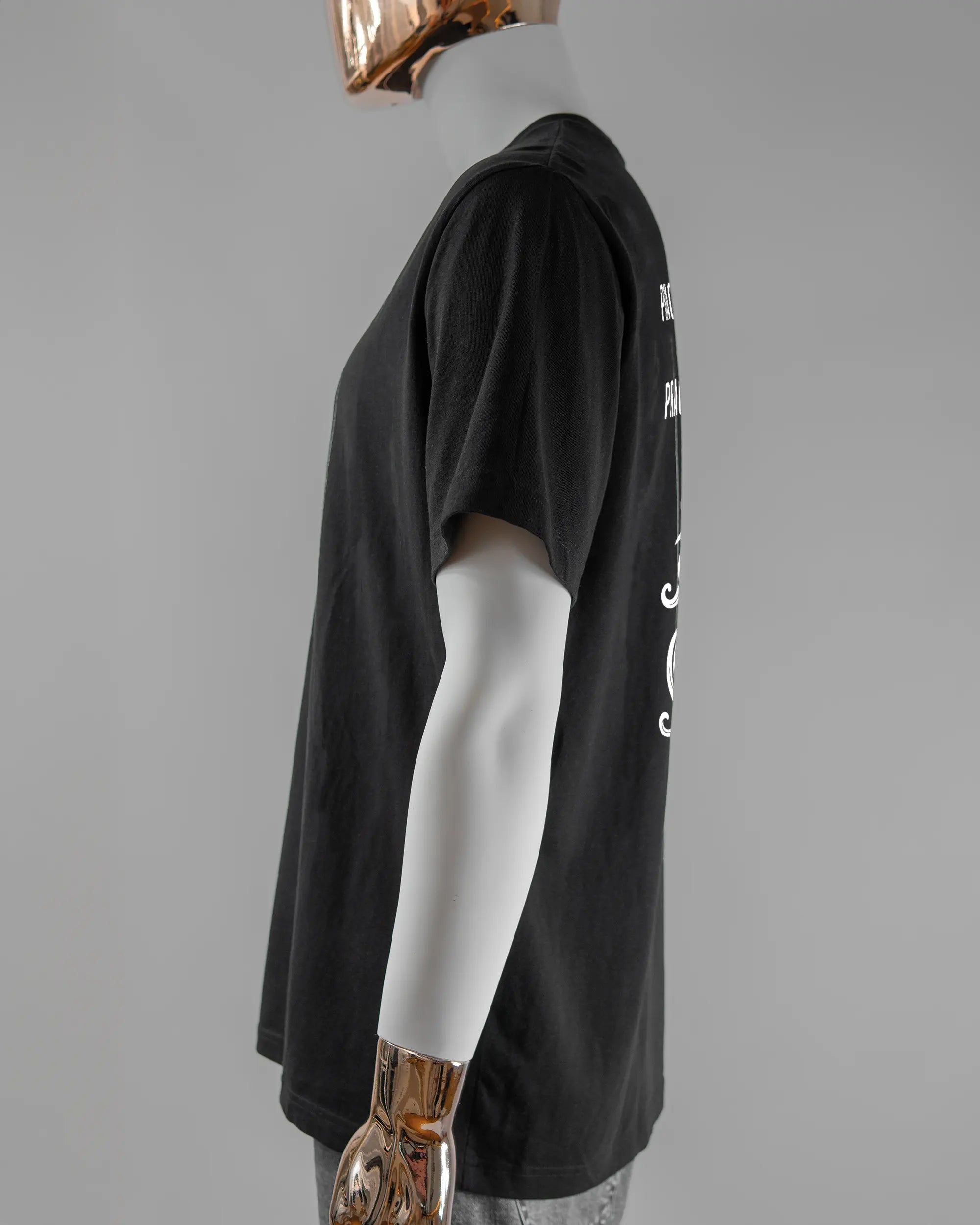 Seitenansicht des Organic Unisex T-Shirt Relaxed von Maondo mit dem Design Trachtentanz hinten in der Farbe Black und in der Größe L getragen von einer maskulinen Puppe