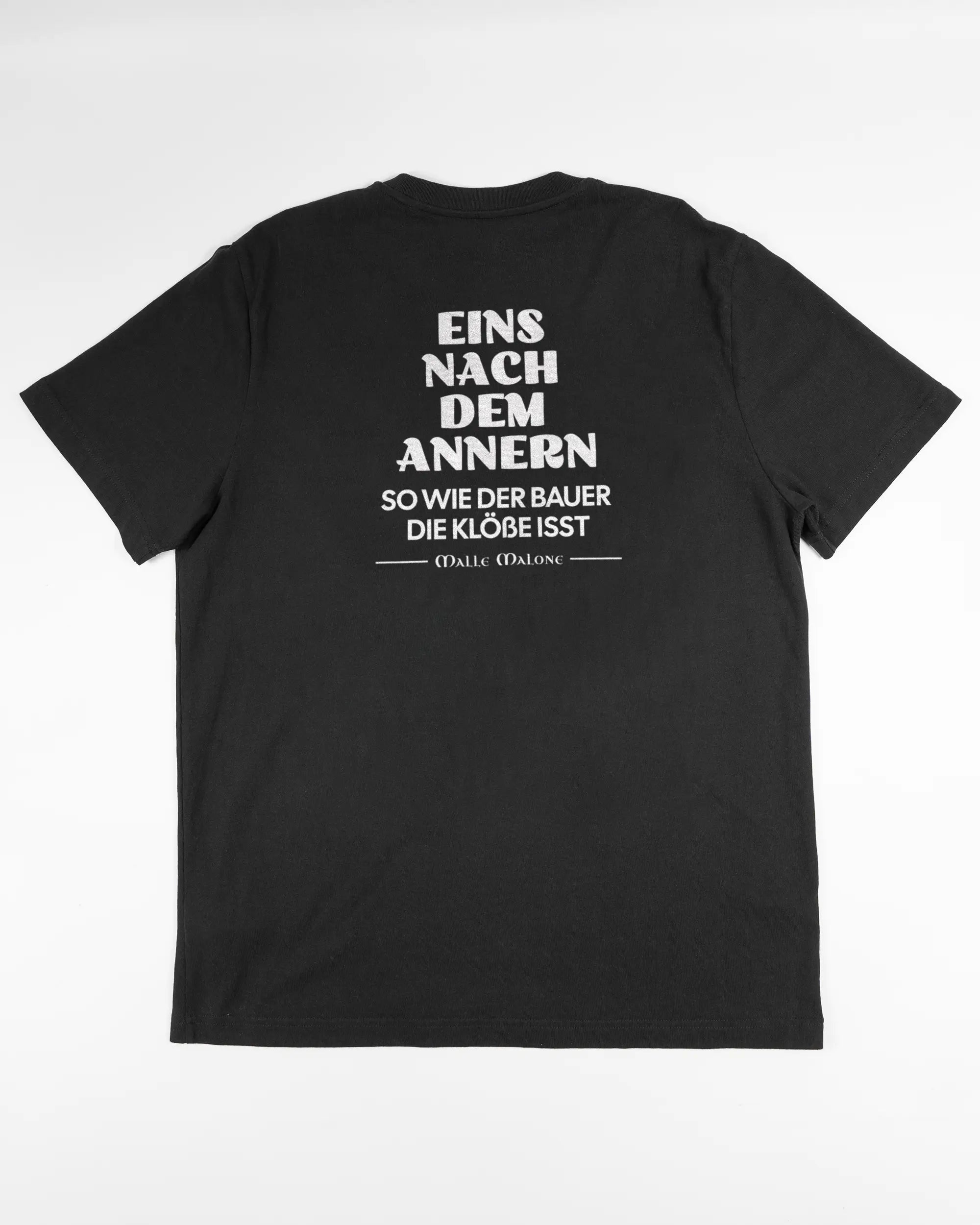 Rückseite des Organic Unisex T-Shirt Relaxed von Maondo mit dem Design Eins nach dem Annern in der Farbe Black und in der Größe L flach auf den Boden gelegt