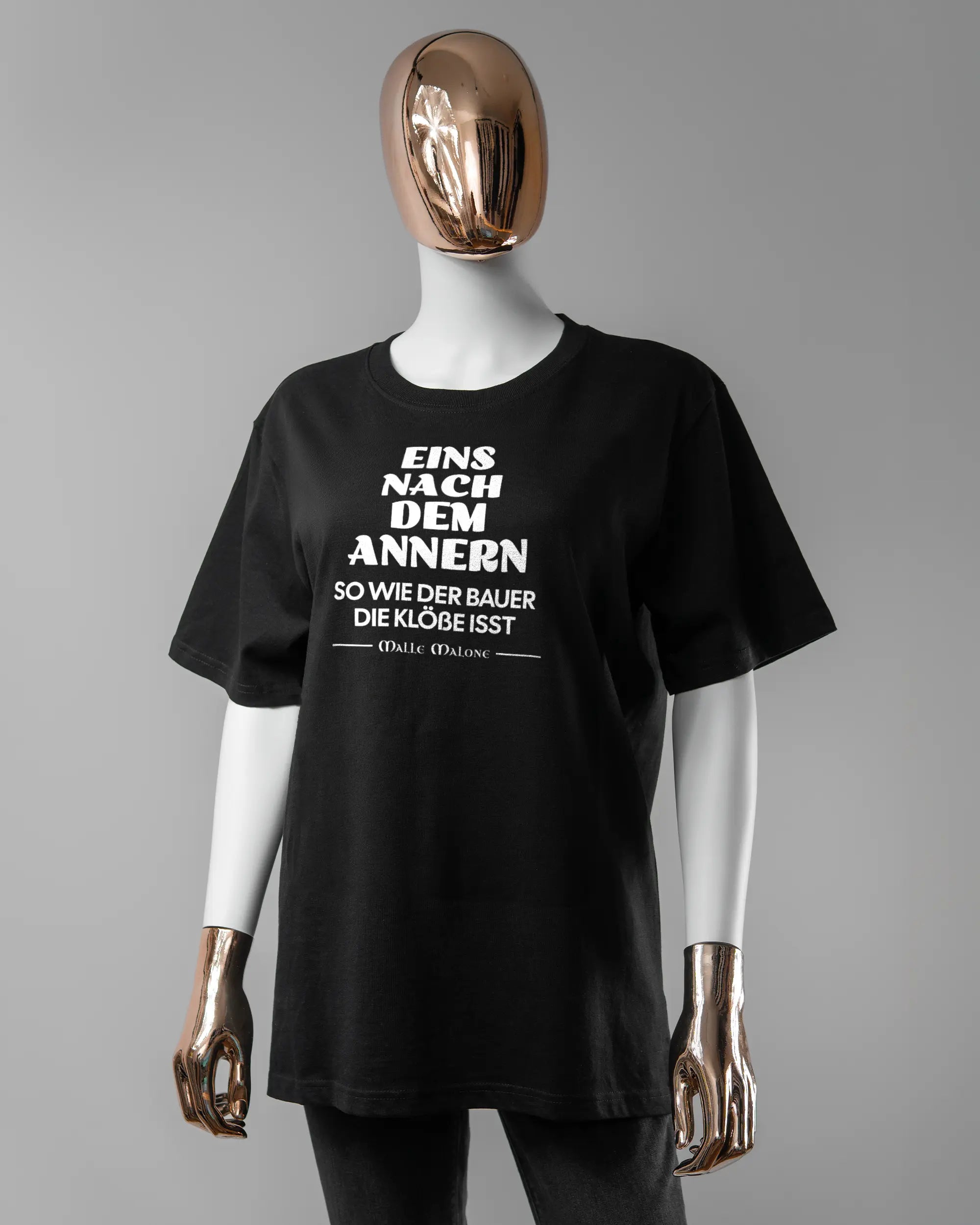 Vorderseite des Organic Unisex T-Shirt Relaxed von Maondo mit dem Design Eins nach dem Annern in der Farbe Black und in der Größe S getragen von einer femininen Puppe