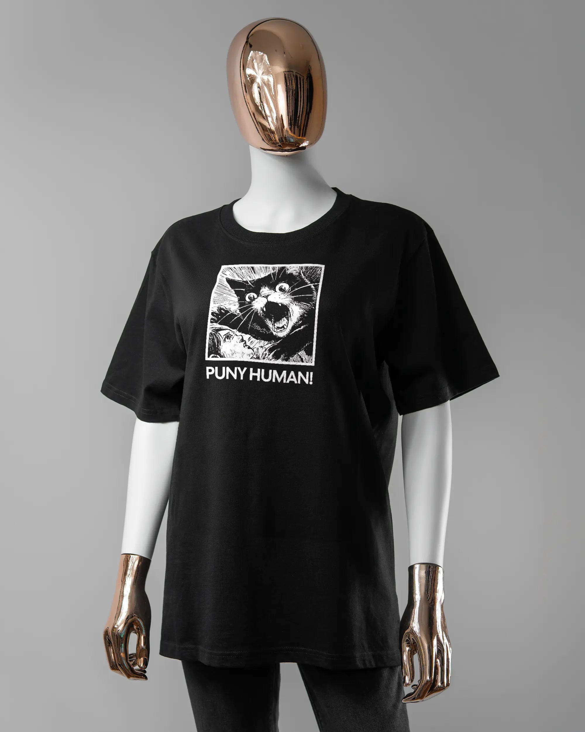Vorderseite des Organic Unisex T-Shirt Relaxed von Maondo mit dem Design Puny Human in der Farbe Black und in der Größe S getragen von einer femininen Puppe