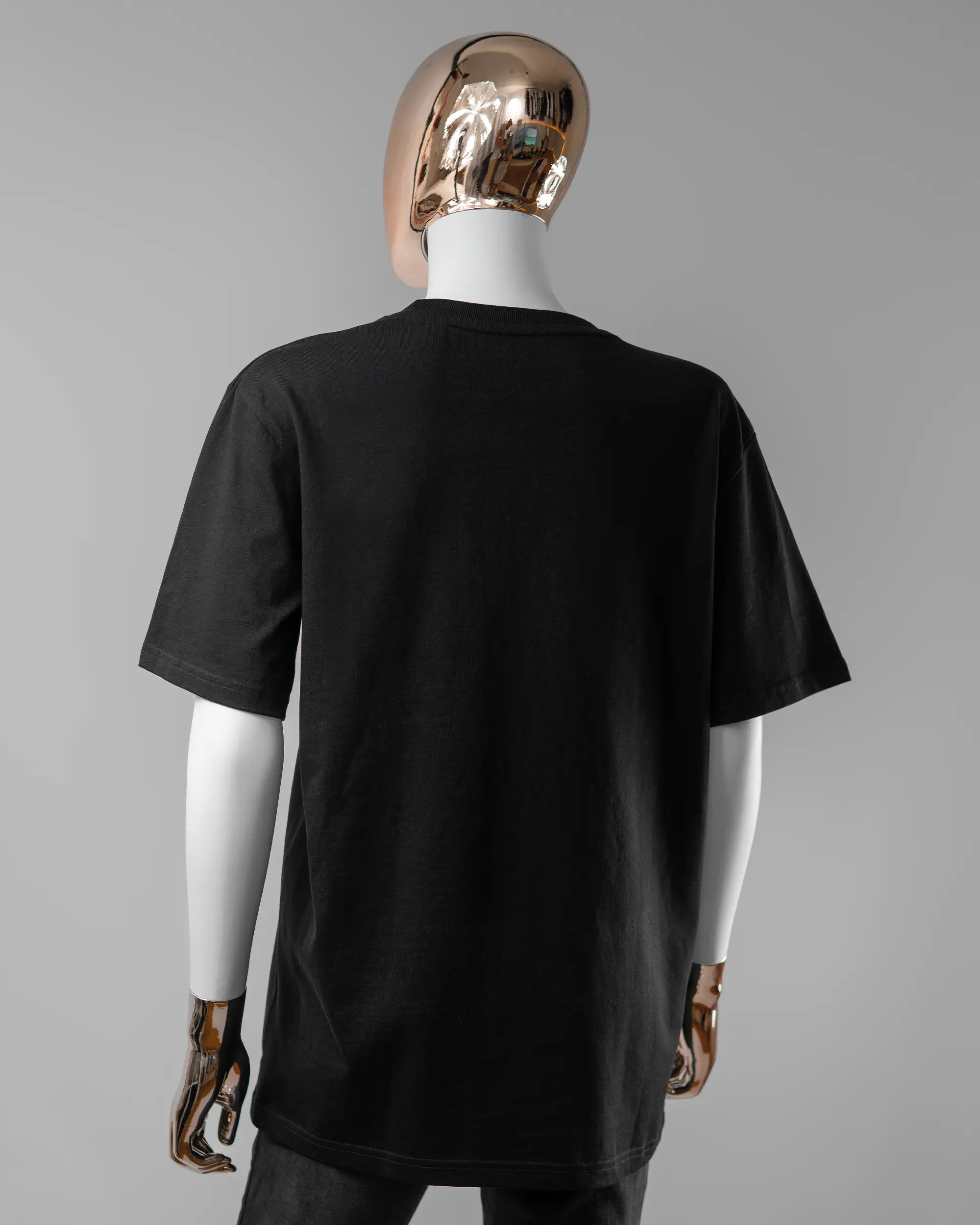 Rückseite des Organic Unisex T-Shirt Relaxed von Maondo ohne Motiv in der Farbe Black und in der Größe S getragen von einer femininen Puppe