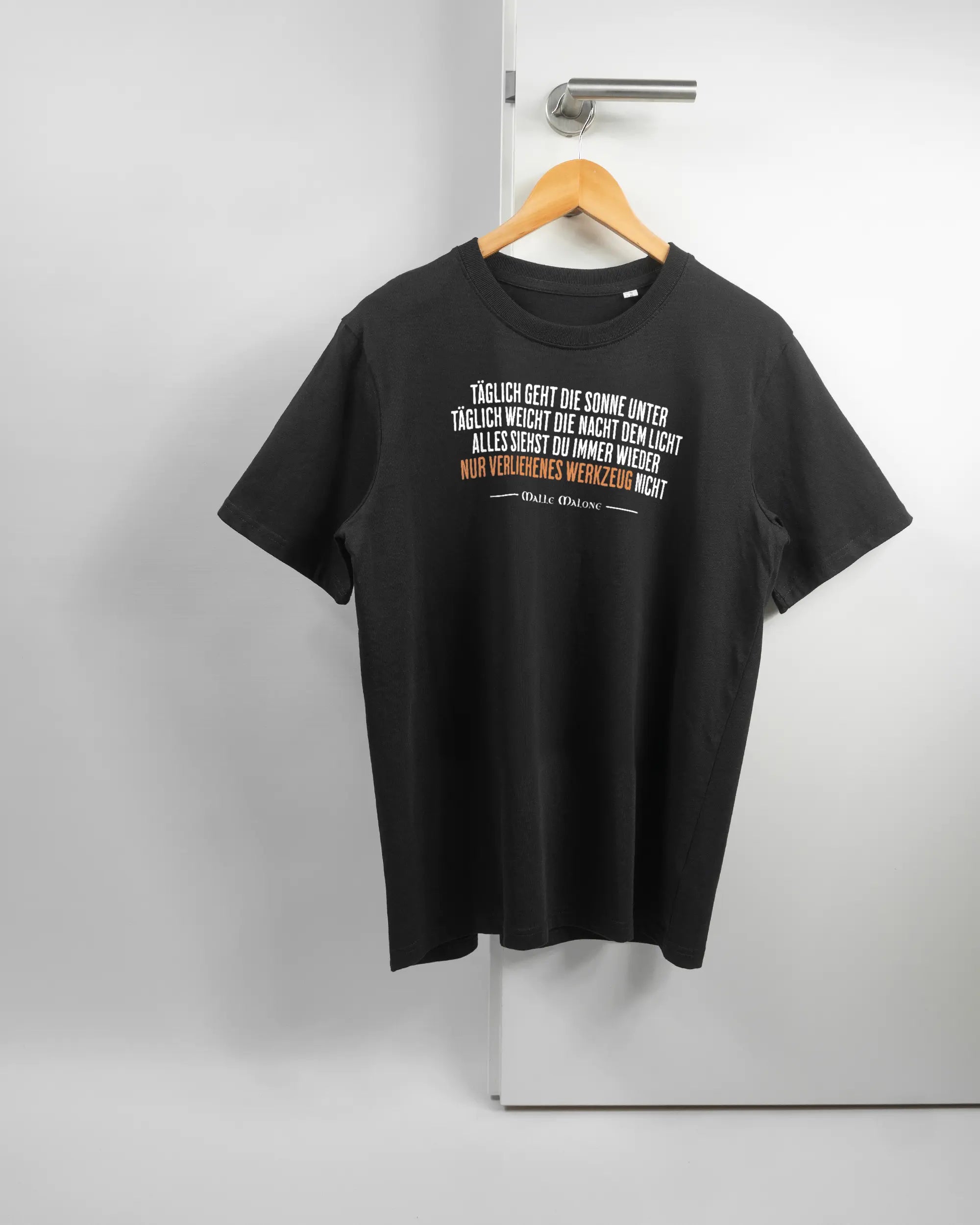 Vorderseite des Organic Unisex T-Shirt Relaxed von Maondo mit dem Design Wegzeug in der Farbe Black und in der Größe S auf einem Bügel an der Türklinke aufgehängt