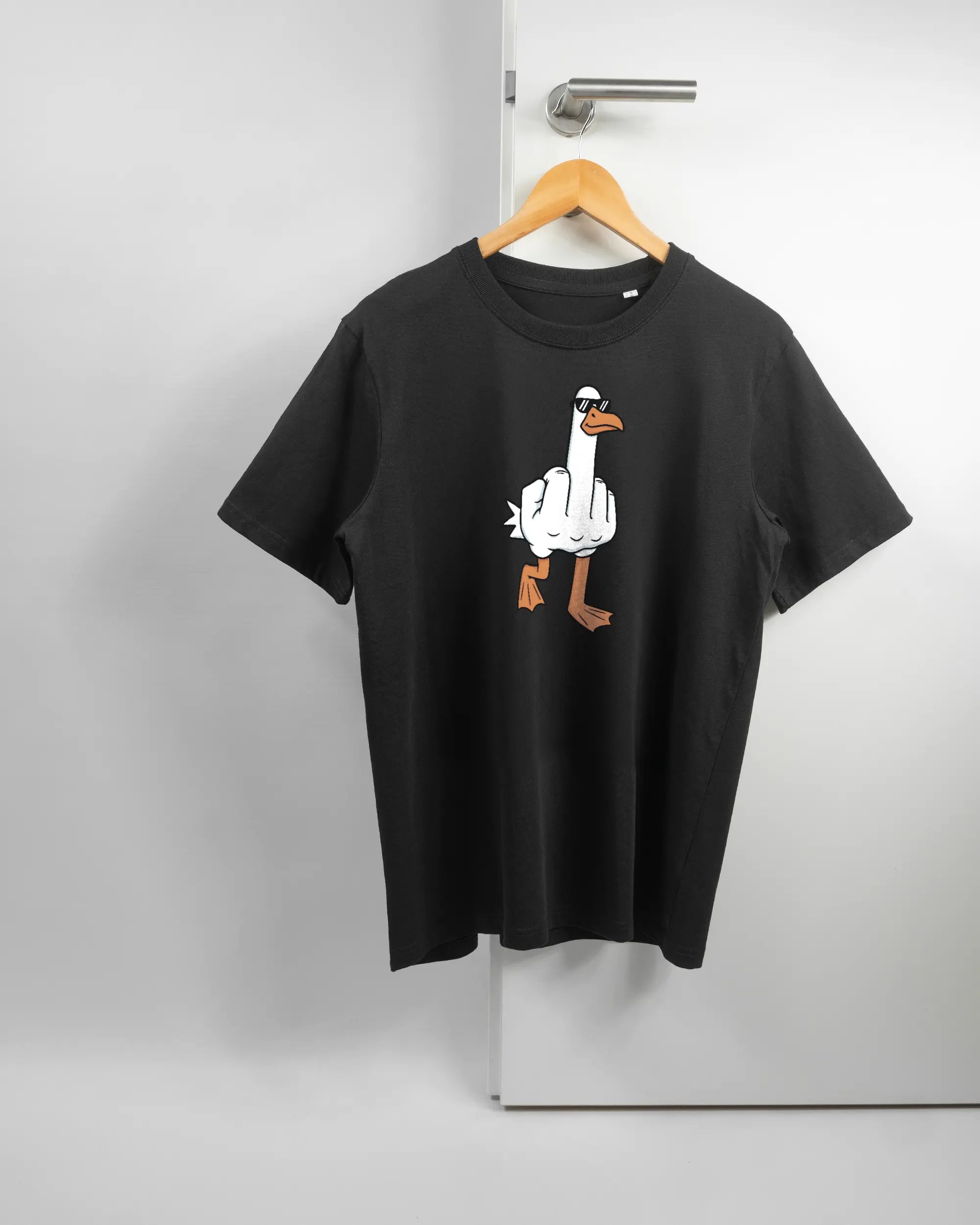 Vorderseite des Organic Unisex T-Shirt Relaxed von Maondo mit dem Design I give a duck in der Farbe Black und in der Größe S auf einem Bügel an der Türklinke aufgehängt
