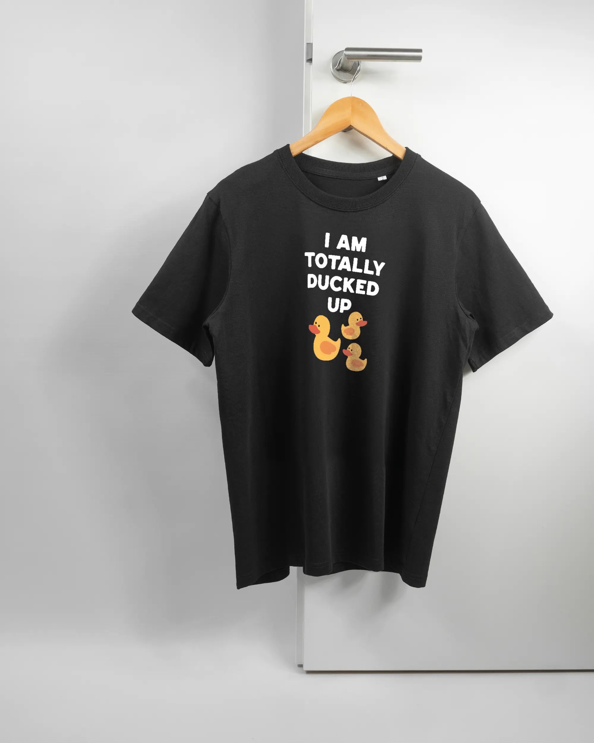 Vorderseite des Organic Unisex T-Shirt Relaxed von Maondo mit dem Design Ducked Up in der Farbe Black und in der Größe S auf einem Bügel an der Türklinke aufgehängt