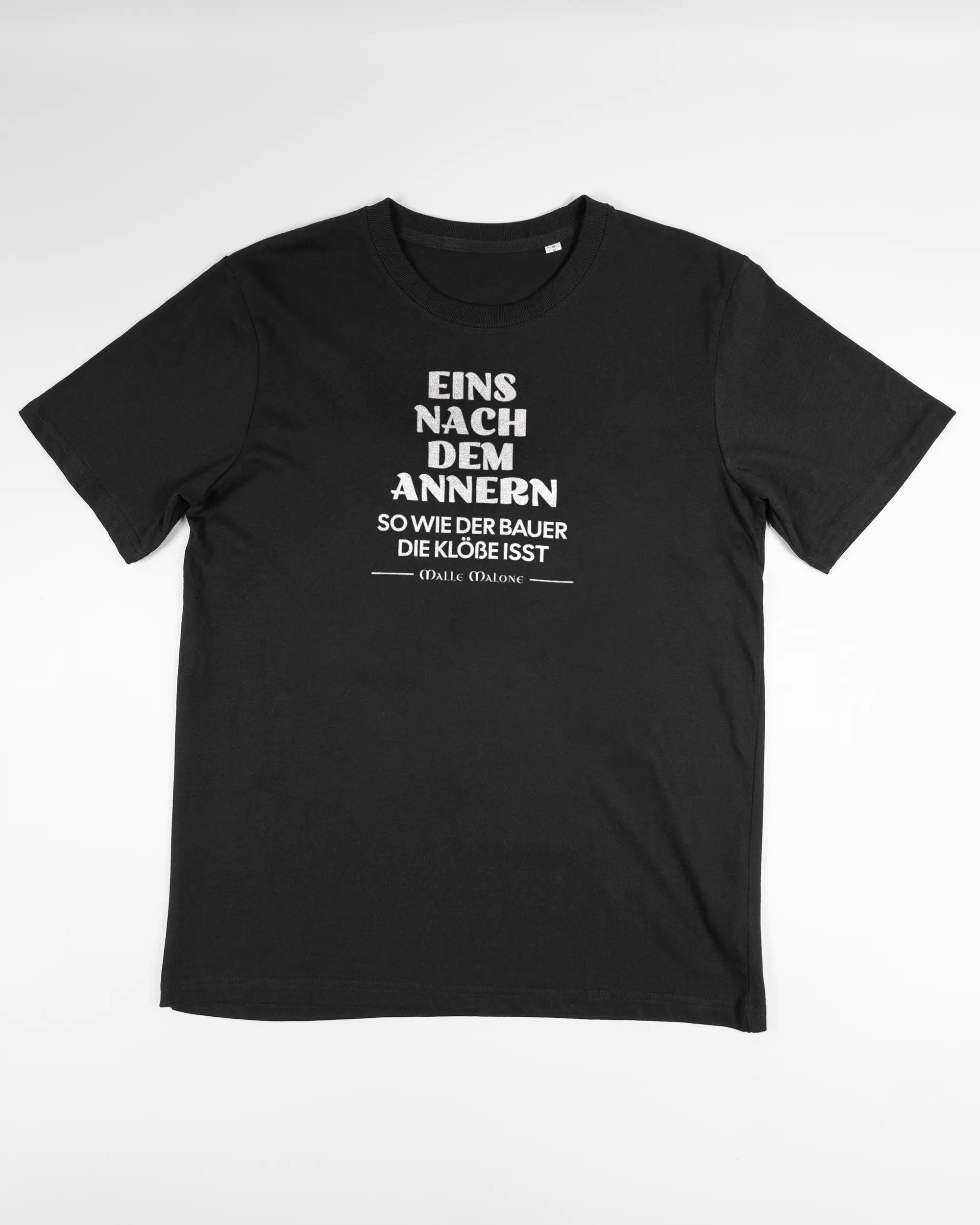 Vorderseite des Organic Unisex T-Shirt Relaxed von Maondo mit dem Design Eins nach dem Annern in der Farbe Black und in der Größe S flach auf den Boden gelegt