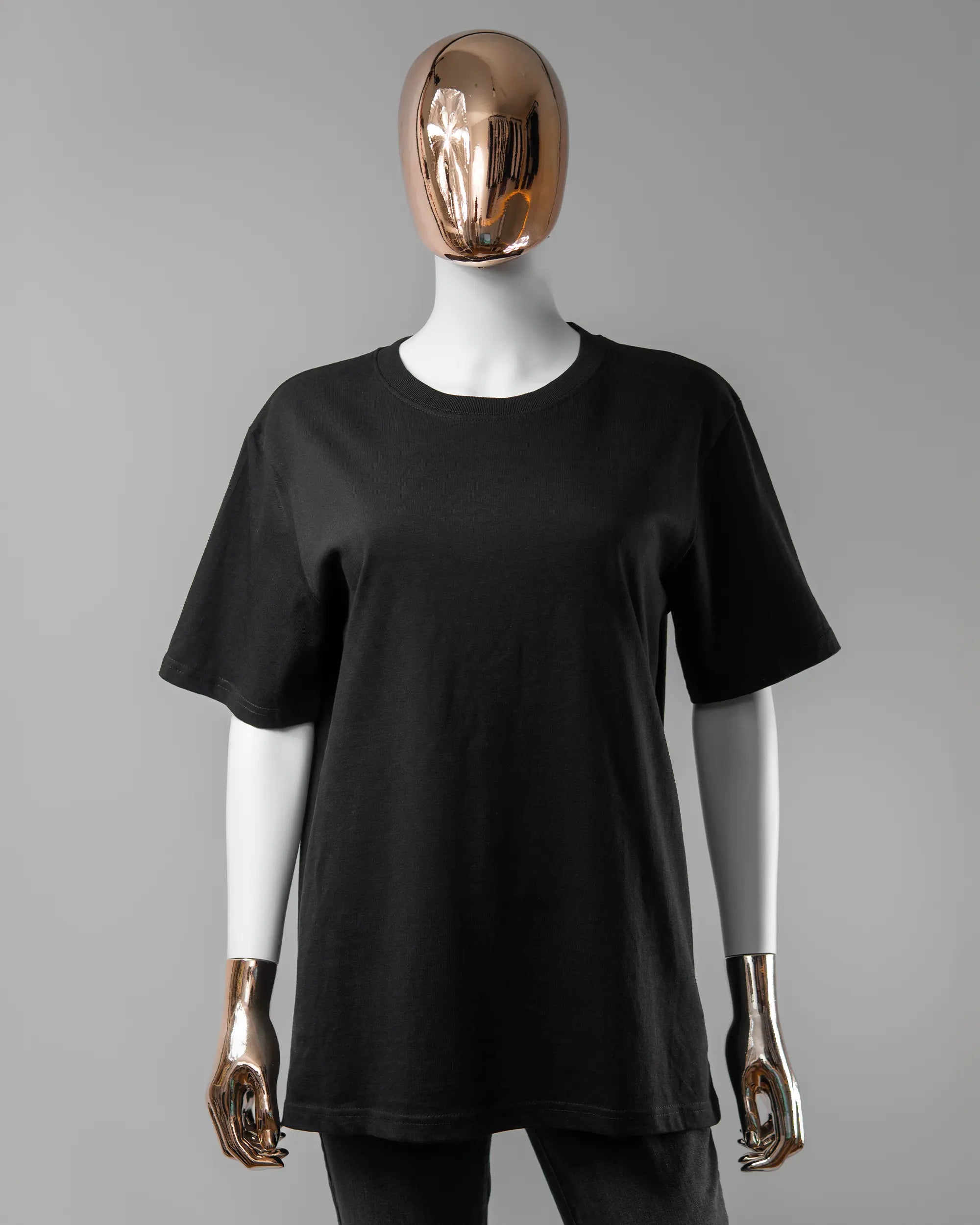 Vorderseite des Organic Unisex T-Shirt Relaxed von Maondo ohne Motiv in der Farbe Black und in der Größe S getragen von einer femininen Puppe