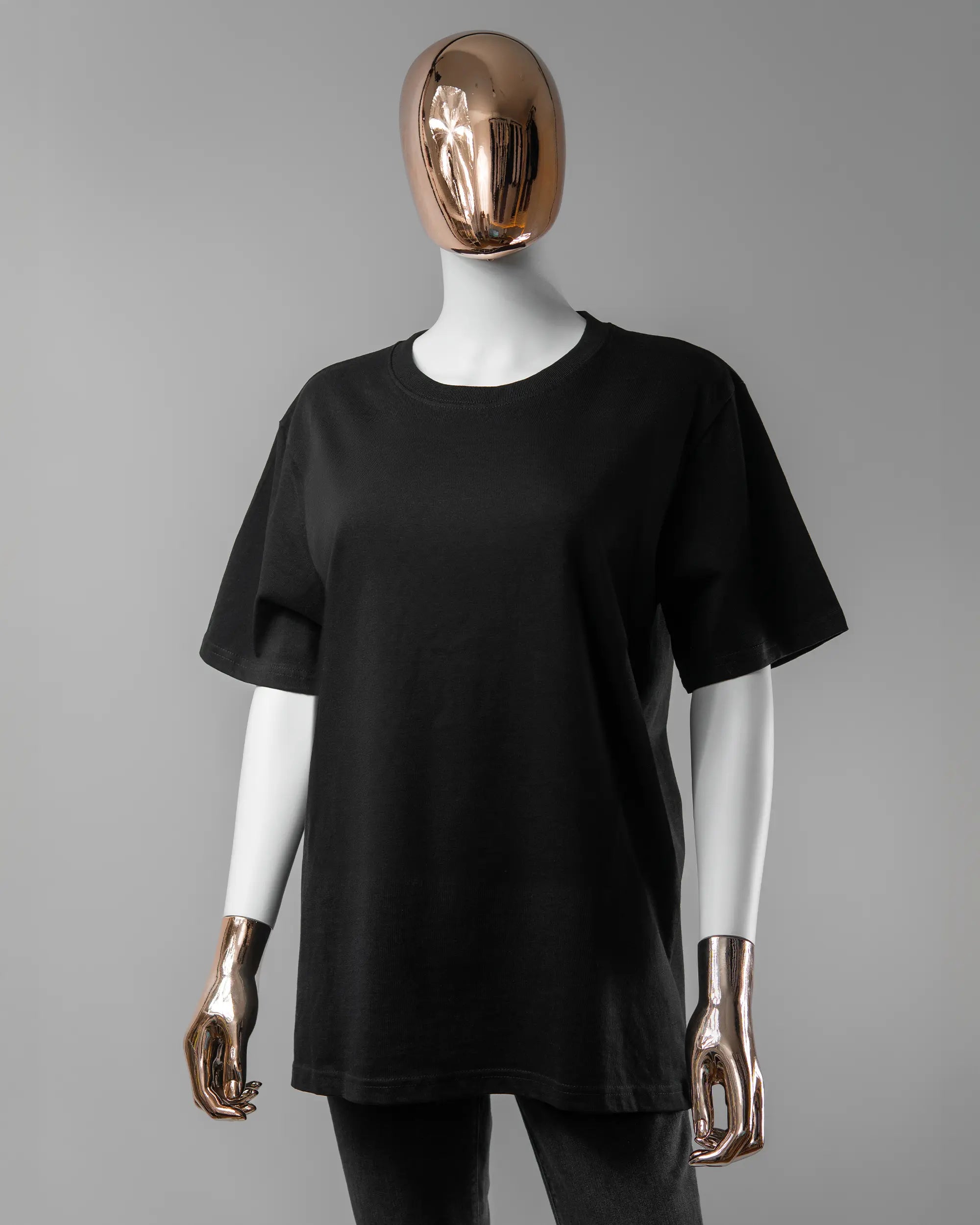 Vorderseite des Organic Unisex T-Shirt Relaxed von Maondo ohne Motiv in der Farbe Black und in der Größe S getragen von einer femininen Puppe