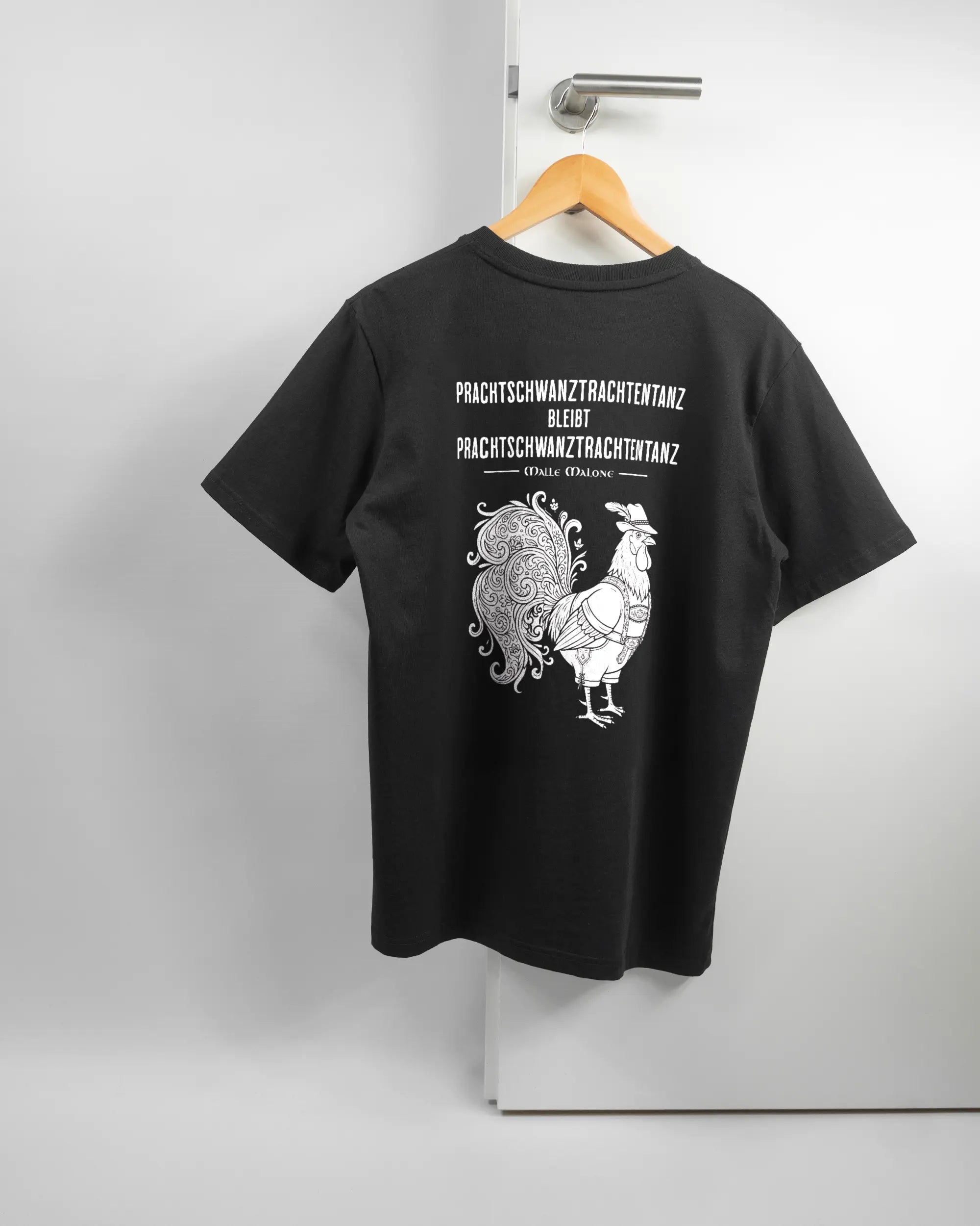 Rückseite des Organic Unisex T-Shirt Relaxed von Maondo mit dem Design Trachtentanz in der Farbe Black und in der Größe S auf einem Bügel an der Türklinke aufgehängt