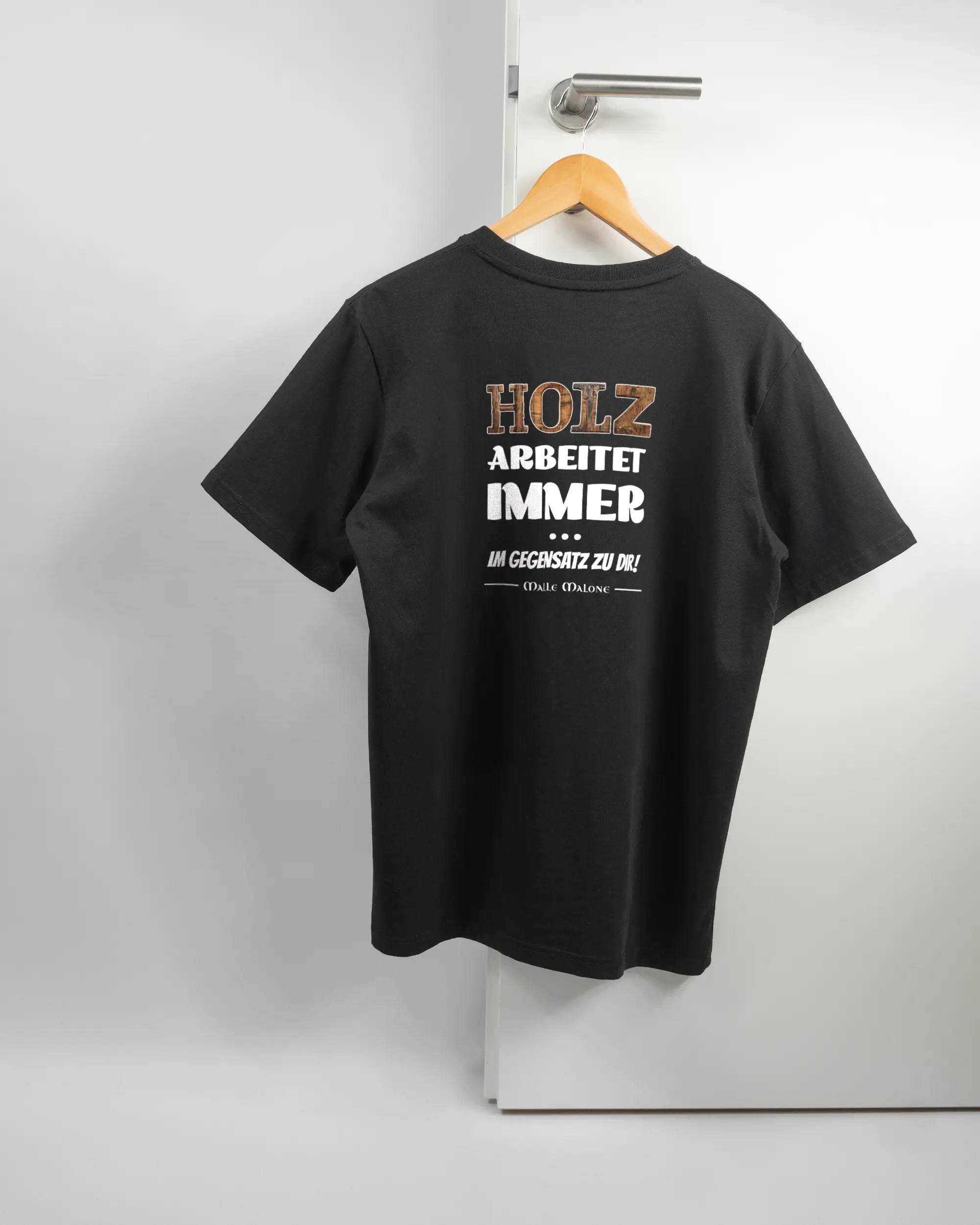 Rückseite des Organic Unisex T-Shirt Relaxed von Maondo mit dem Design Holzarbeit in der Farbe Black und in der Größe S auf einem Bügel an der Türklinke aufgehängt