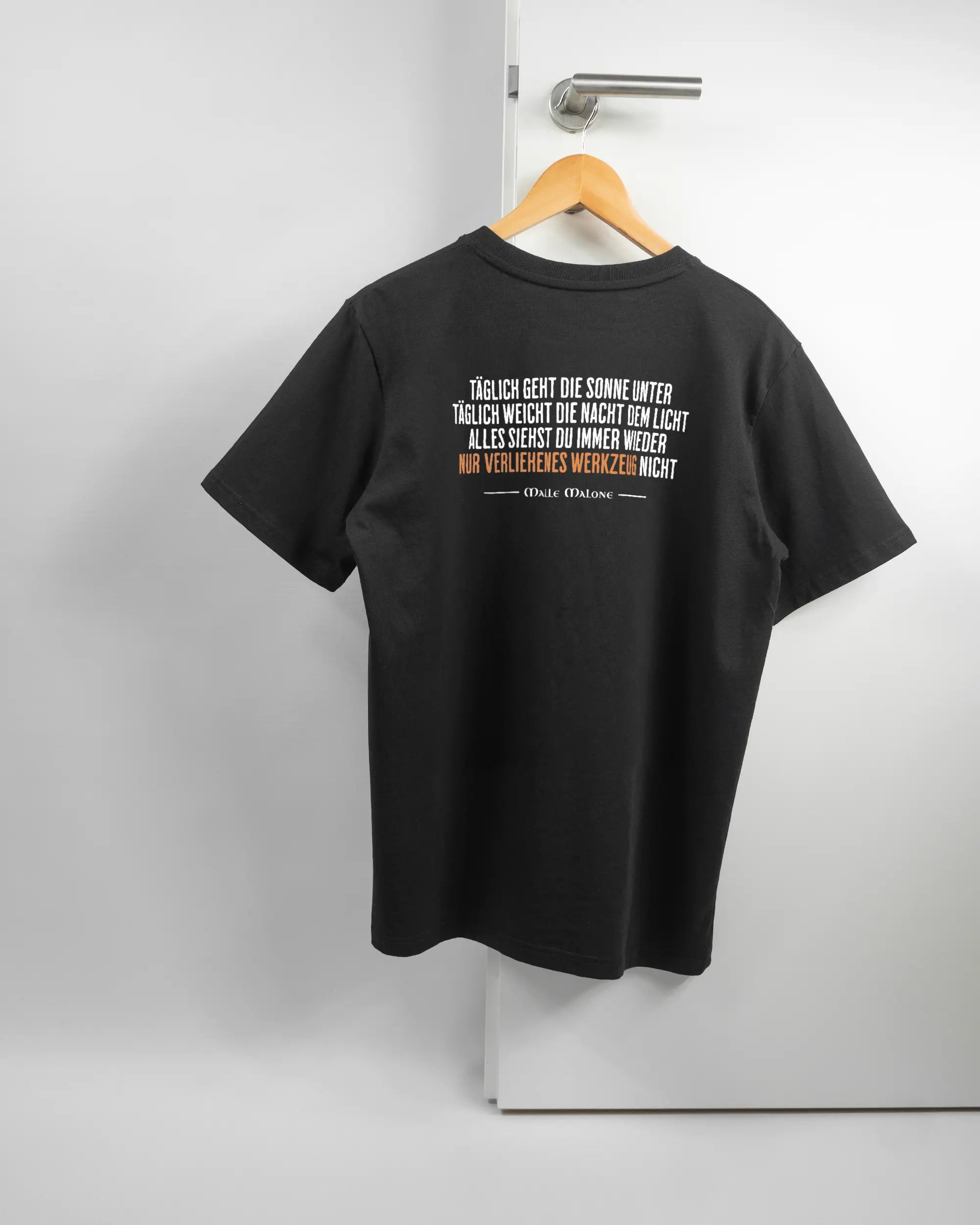 Rückseite des Organic Unisex T-Shirt Relaxed von Maondo mit dem Design Wegzeug in der Farbe Black und in der Größe S auf einem Bügel an der Türklinke aufgehängt
