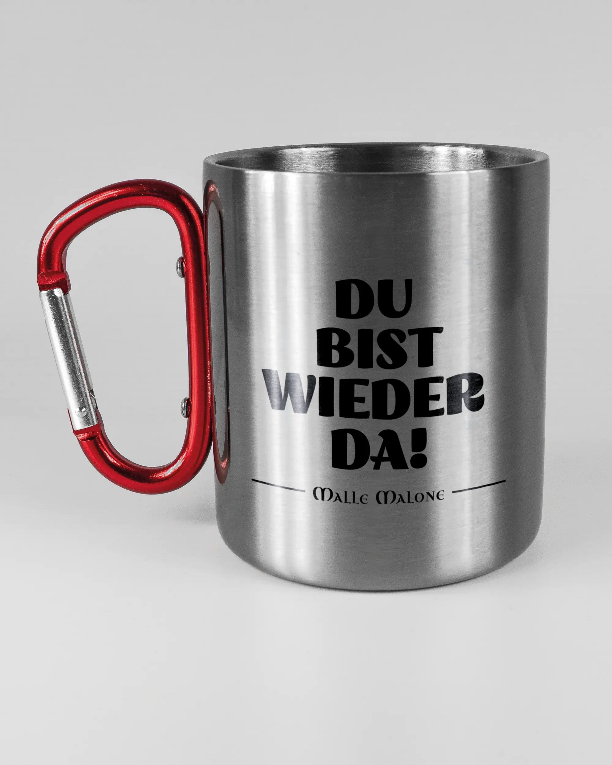 Titelbild, das die linke Seite der beidseitig bedruckten Edelstahltasse von Maondo mit dem Design Wieder da in der Farbe Metallic-Red auf einem Holztisch zeigt