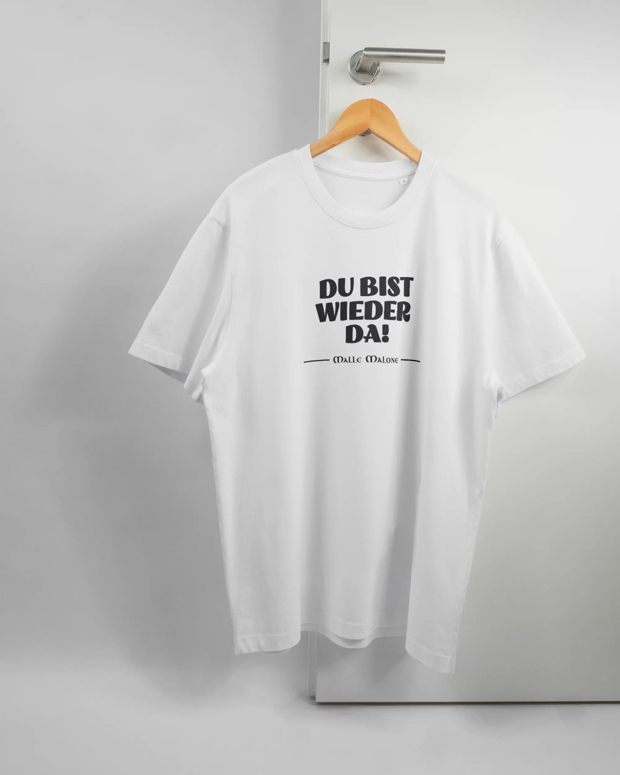 Vorderseite des Organic Unisex T-Shirt Relaxed von Maondo mit dem Design Wieder da in der Farbe White und in der Größe L auf einem Bügel an der Türklinke aufgehängt