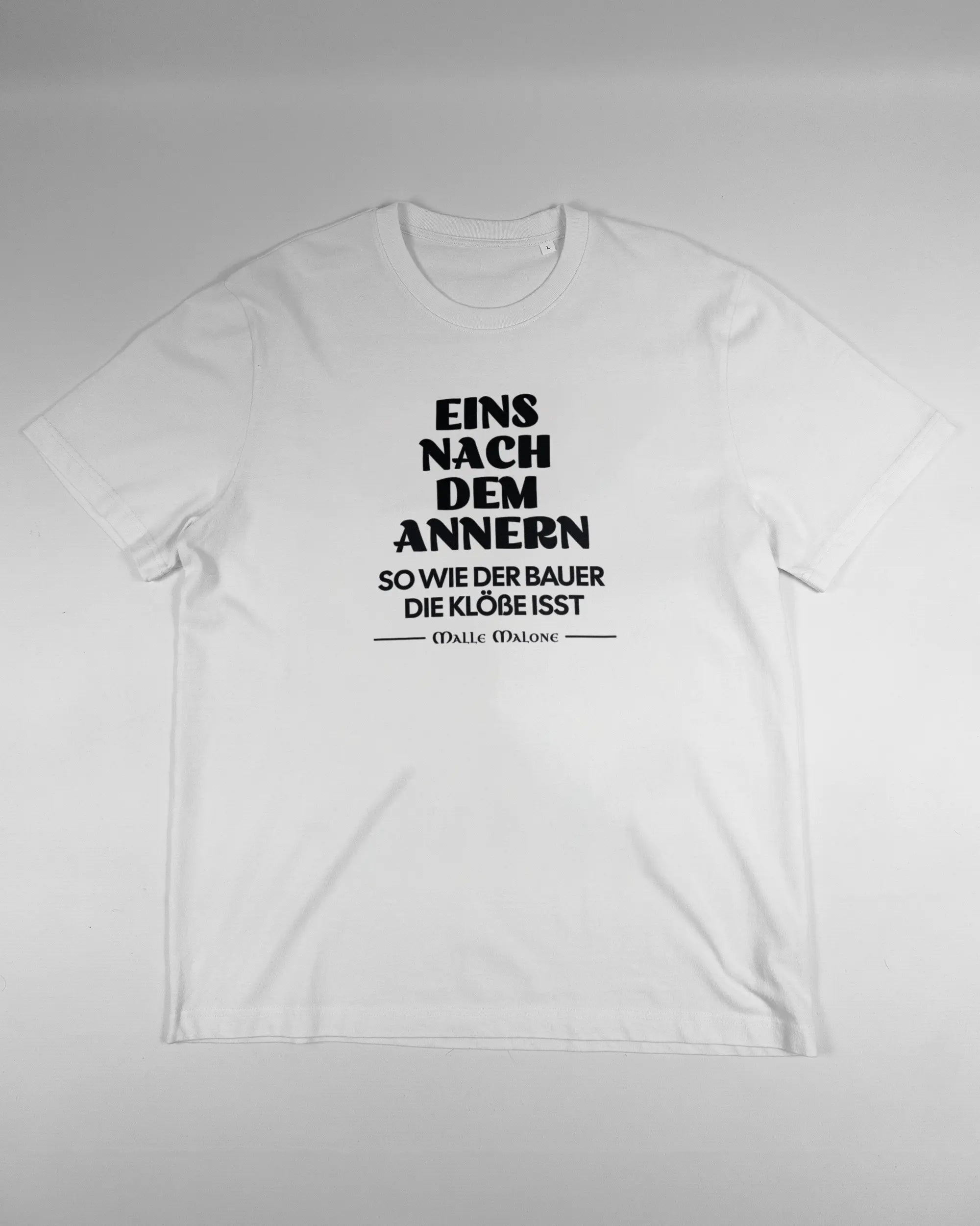 Vorderseite des Organic Unisex T-Shirt Relaxed von Maondo mit dem Design Eins nach dem Annern in der Farbe White und in der Größe L flach auf den Boden gelegt