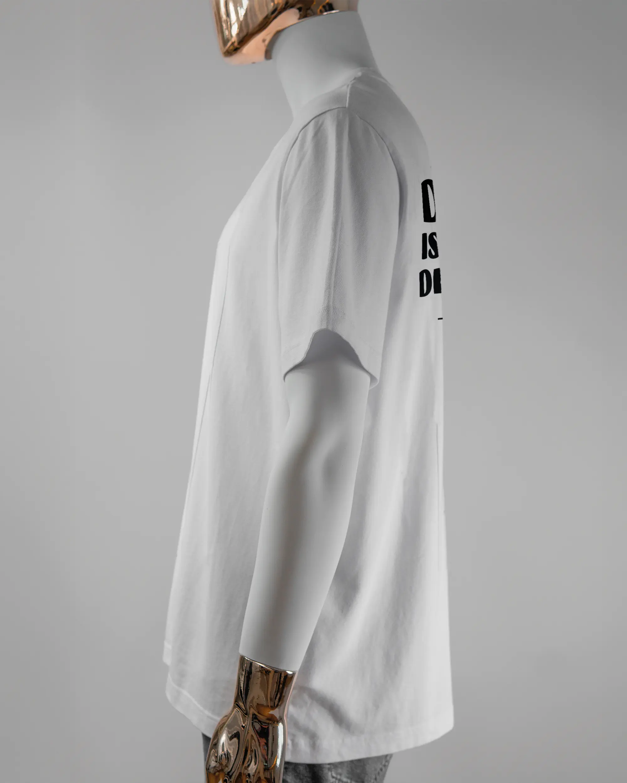 Seitenansicht des Organic Unisex T-Shirt Relaxed von Maondo mit dem Design Keine Eile hinten in der Farbe White und in der Größe L getragen von einer maskulinen Puppe