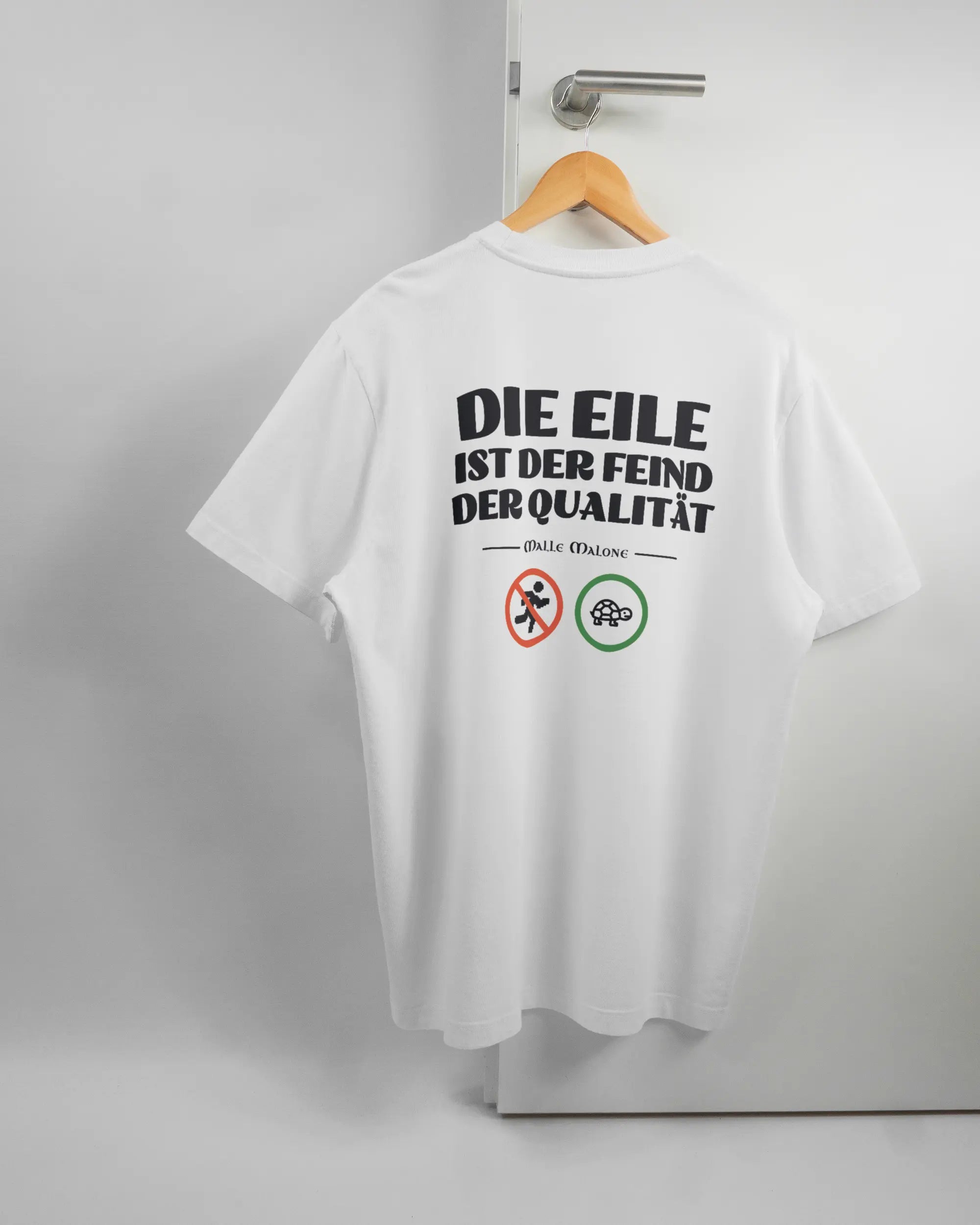 Rückseite des Organic Unisex T-Shirt Relaxed von Maondo mit dem Design Keine Eile in der Farbe White und in der Größe L auf einem Bügel an der Türklinke aufgehängt