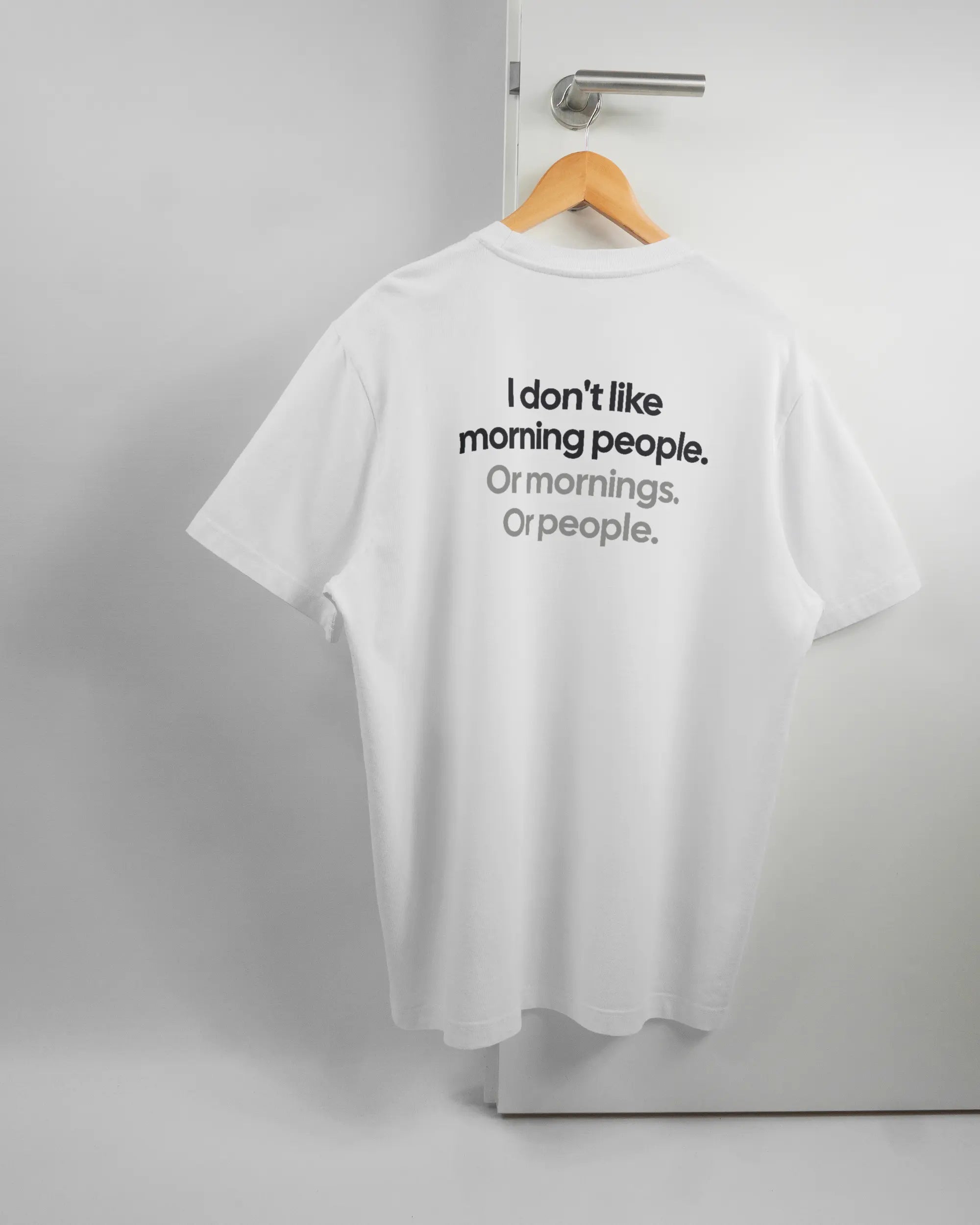 Rückseite des Organic Unisex T-Shirt Relaxed von Maondo mit dem Design Morning Person in der Farbe White und in der Größe L auf einem Bügel an der Türklinke aufgehängt