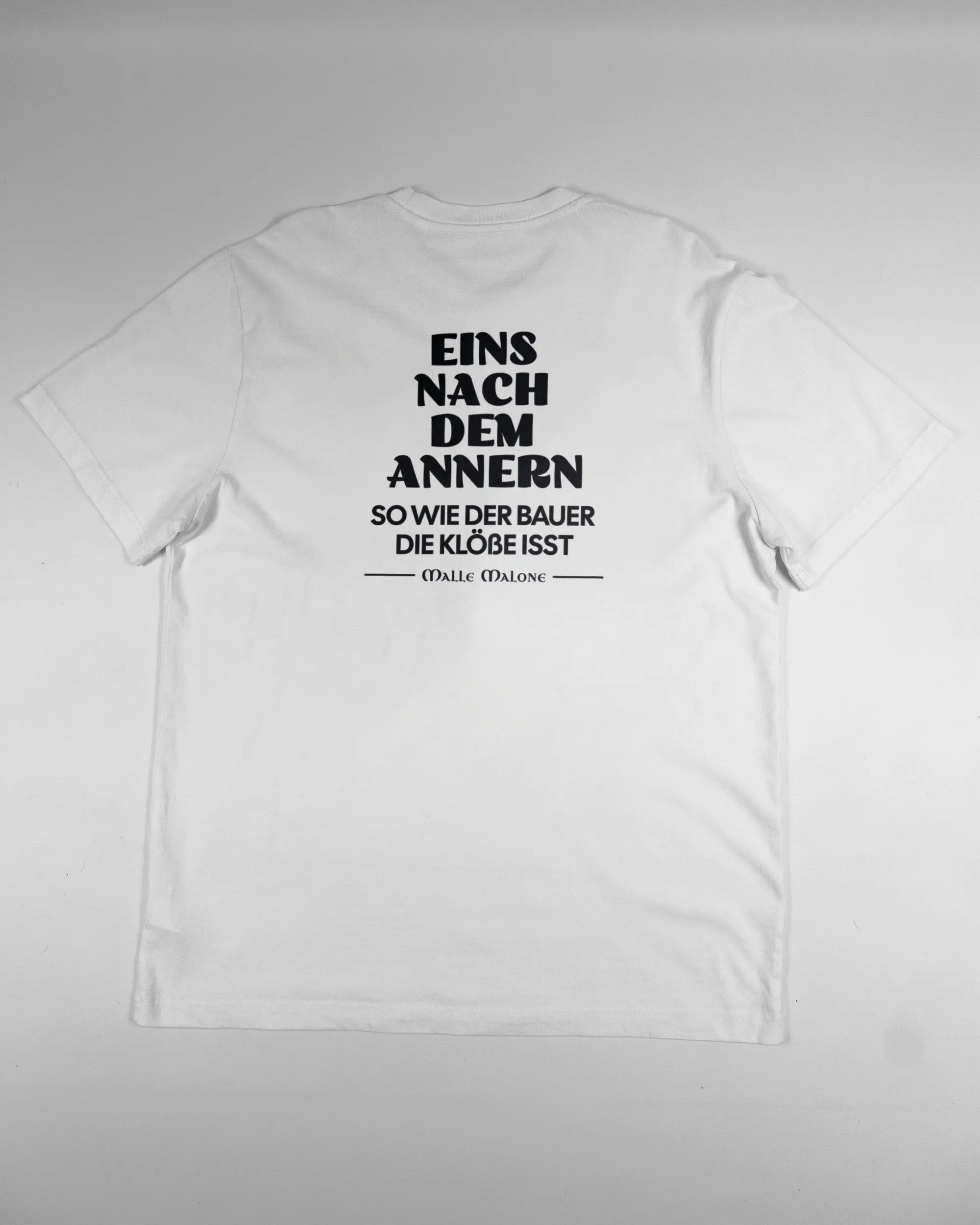 Rückseite des Organic Unisex T-Shirt Relaxed von Maondo mit dem Design Eins nach dem Annern in der Farbe White und in der Größe L flach auf den Boden gelegt