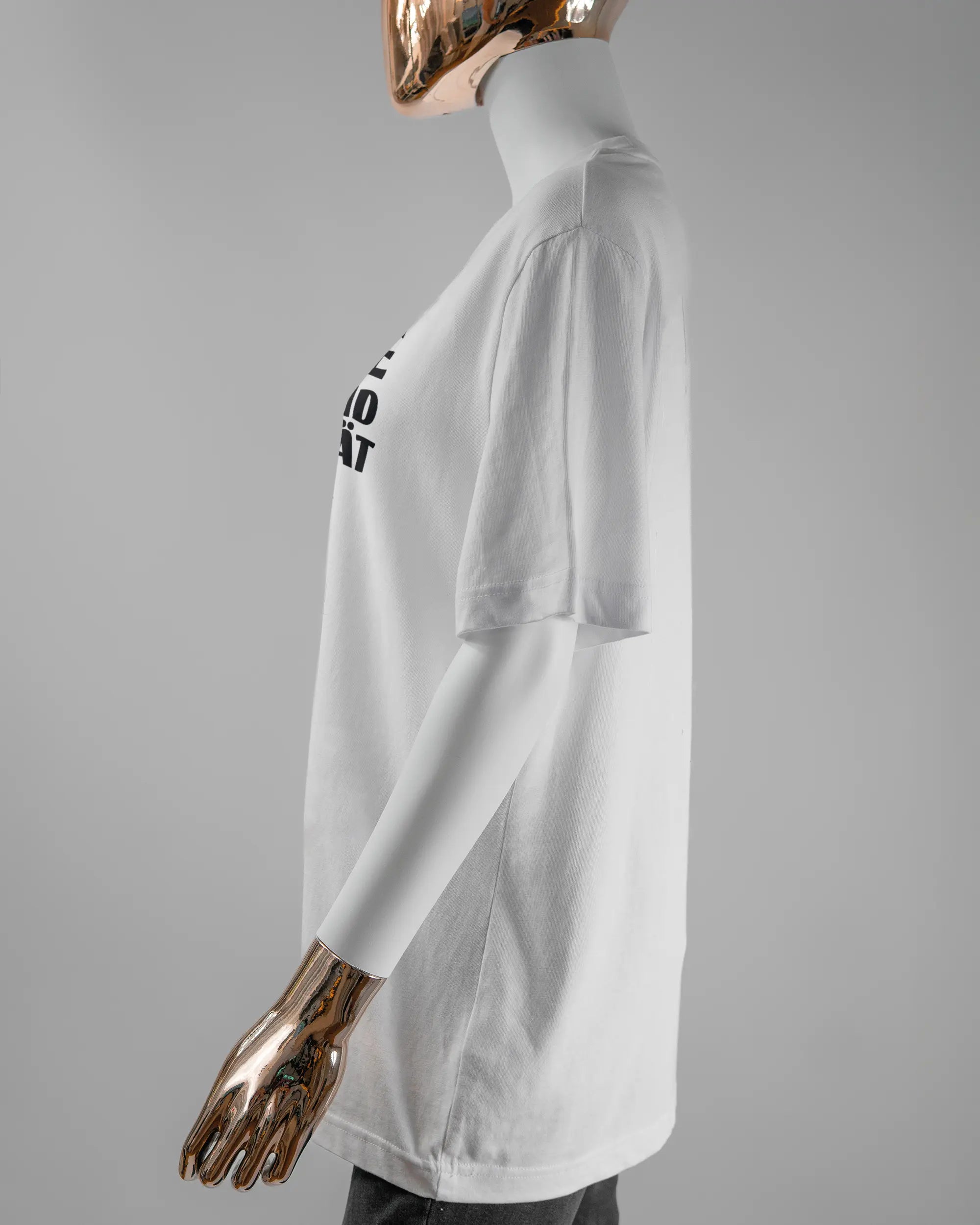 Seitenansicht des Organic Unisex T-Shirt Relaxed von Maondo mit dem Design Keine Eile vorne in der Farbe White und in der Größe S getragen von einer femininen Puppe