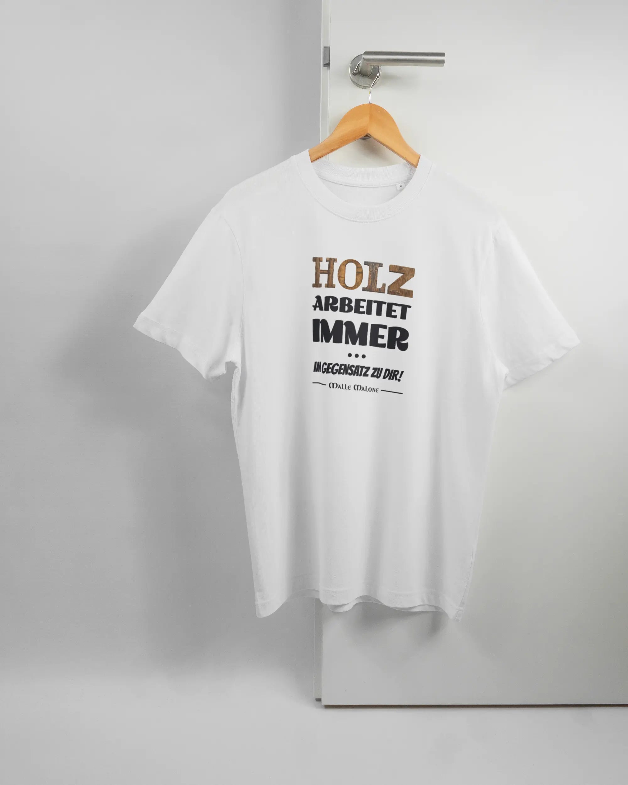 Vorderseite des Organic Unisex T-Shirt Relaxed von Maondo mit dem Design Holzarbeit in der Farbe White und in der Größe S auf einem Bügel an der Türklinke aufgehängt