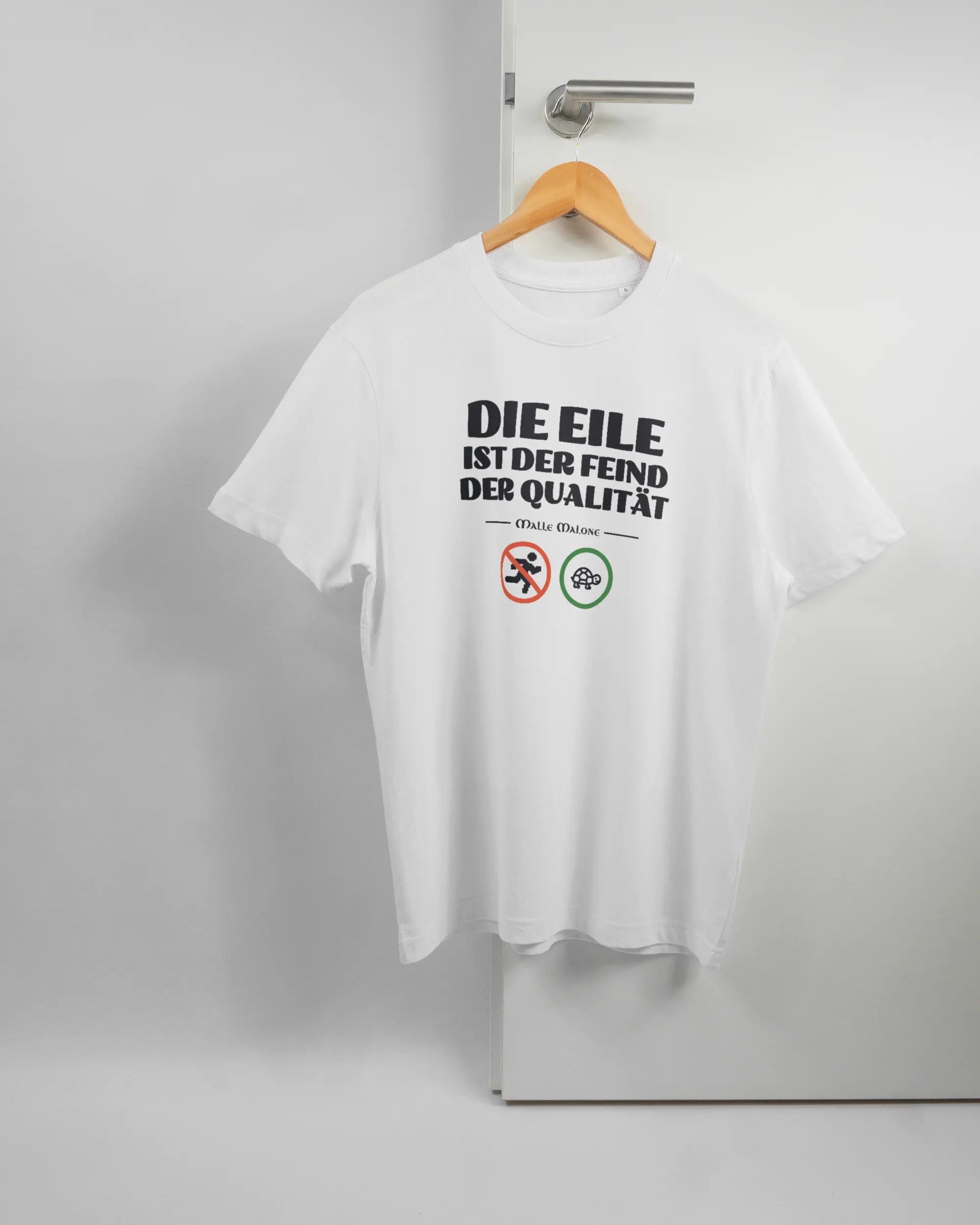 Vorderseite des Organic Unisex T-Shirt Relaxed von Maondo mit dem Design Keine Eile in der Farbe White und in der Größe S auf einem Bügel an der Türklinke aufgehängt