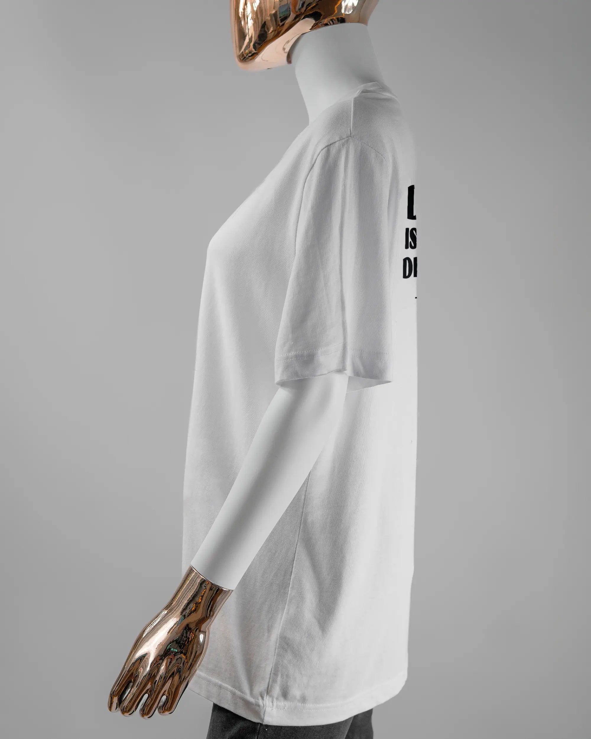 Seitenansicht des Organic Unisex T-Shirt Relaxed von Maondo mit dem Design Keine Eile hinten in der Farbe White und in der Größe S getragen von einer femininen Puppe