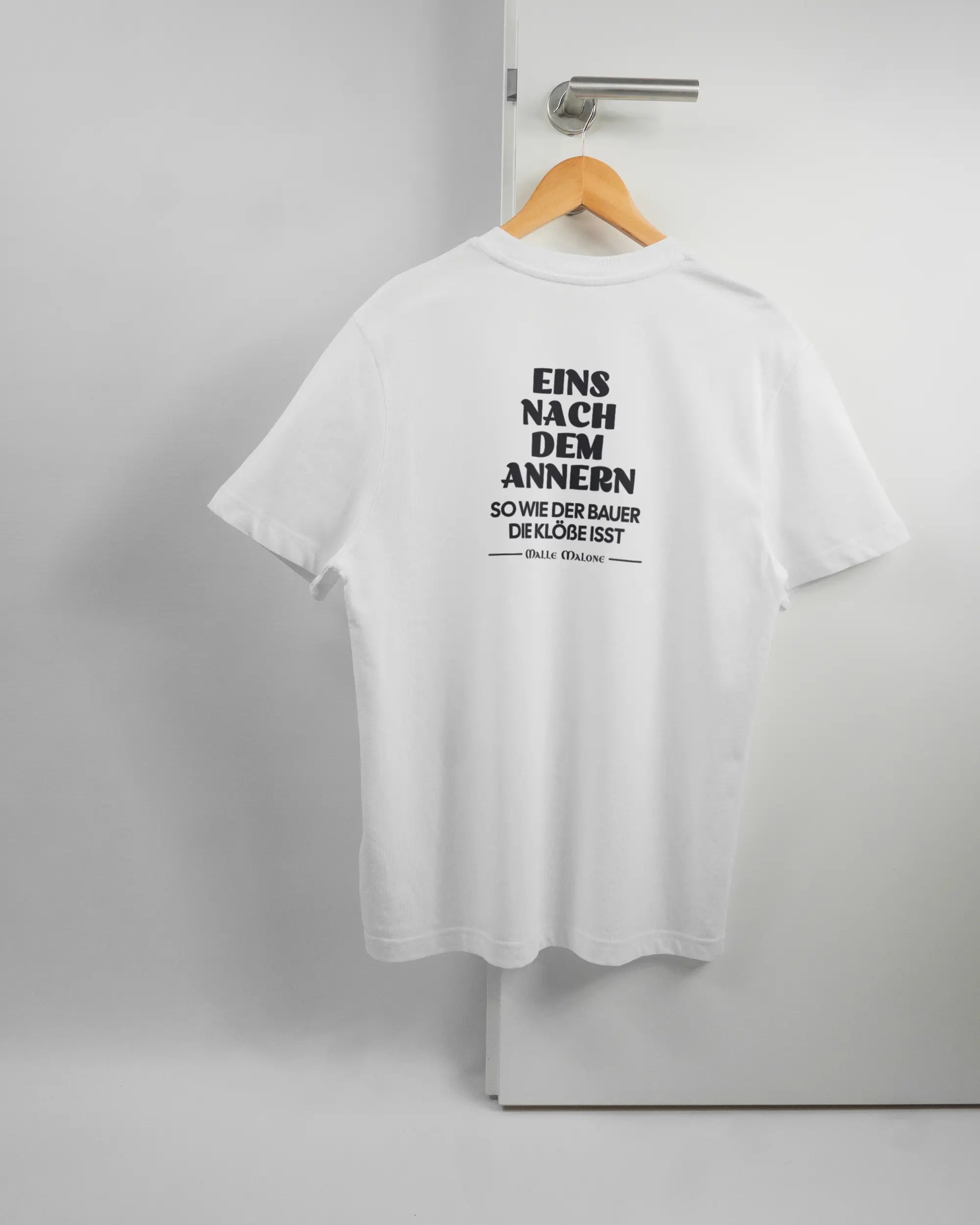 Rückseite des Organic Unisex T-Shirt Relaxed von Maondo mit dem Design Eins nach dem Annern in der Farbe White und in der Größe S auf einem Bügel an der Türklinke aufgehängt