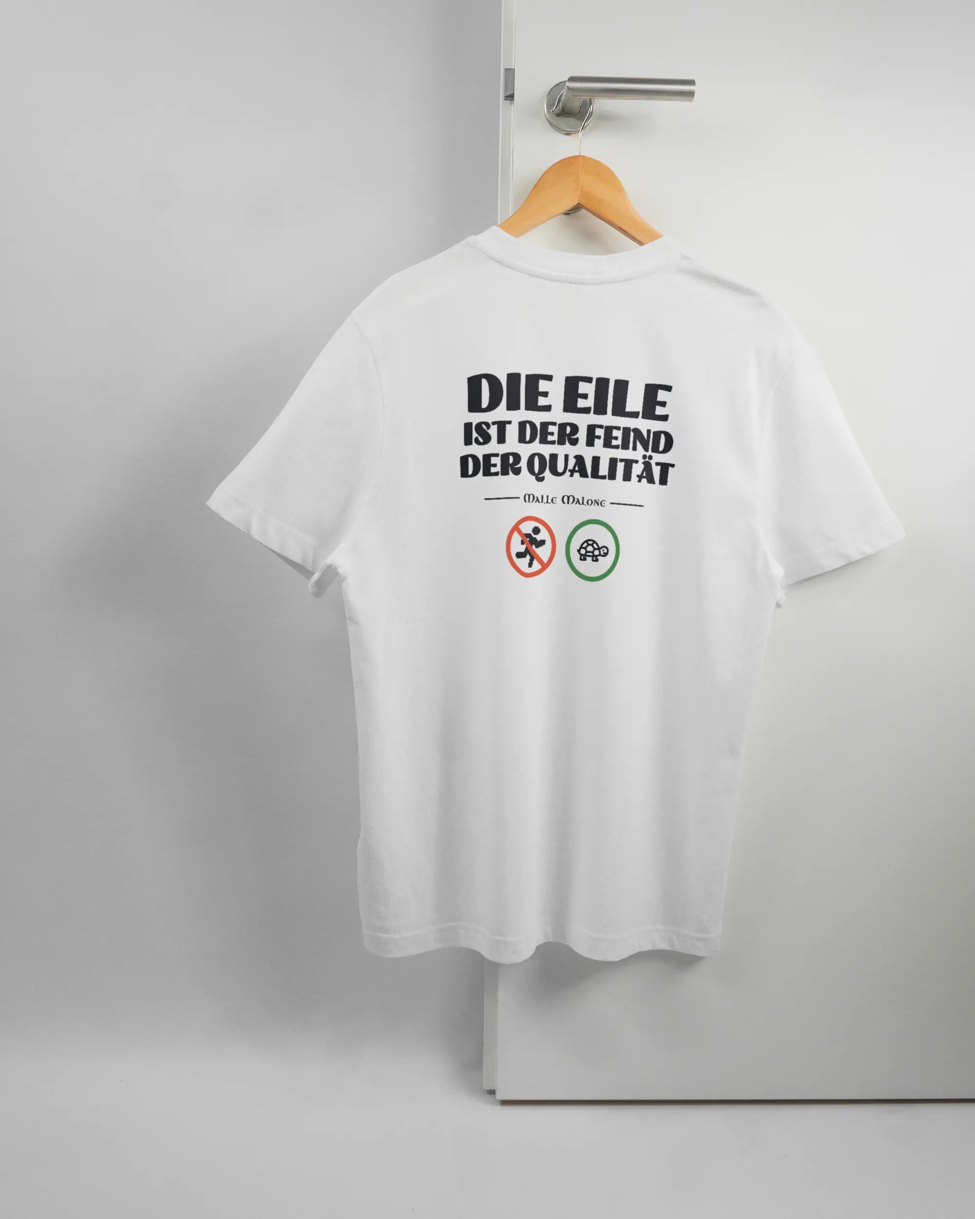 Rückseite des Organic Unisex T-Shirt Relaxed von Maondo mit dem Design Keine Eile in der Farbe White und in der Größe S auf einem Bügel an der Türklinke aufgehängt