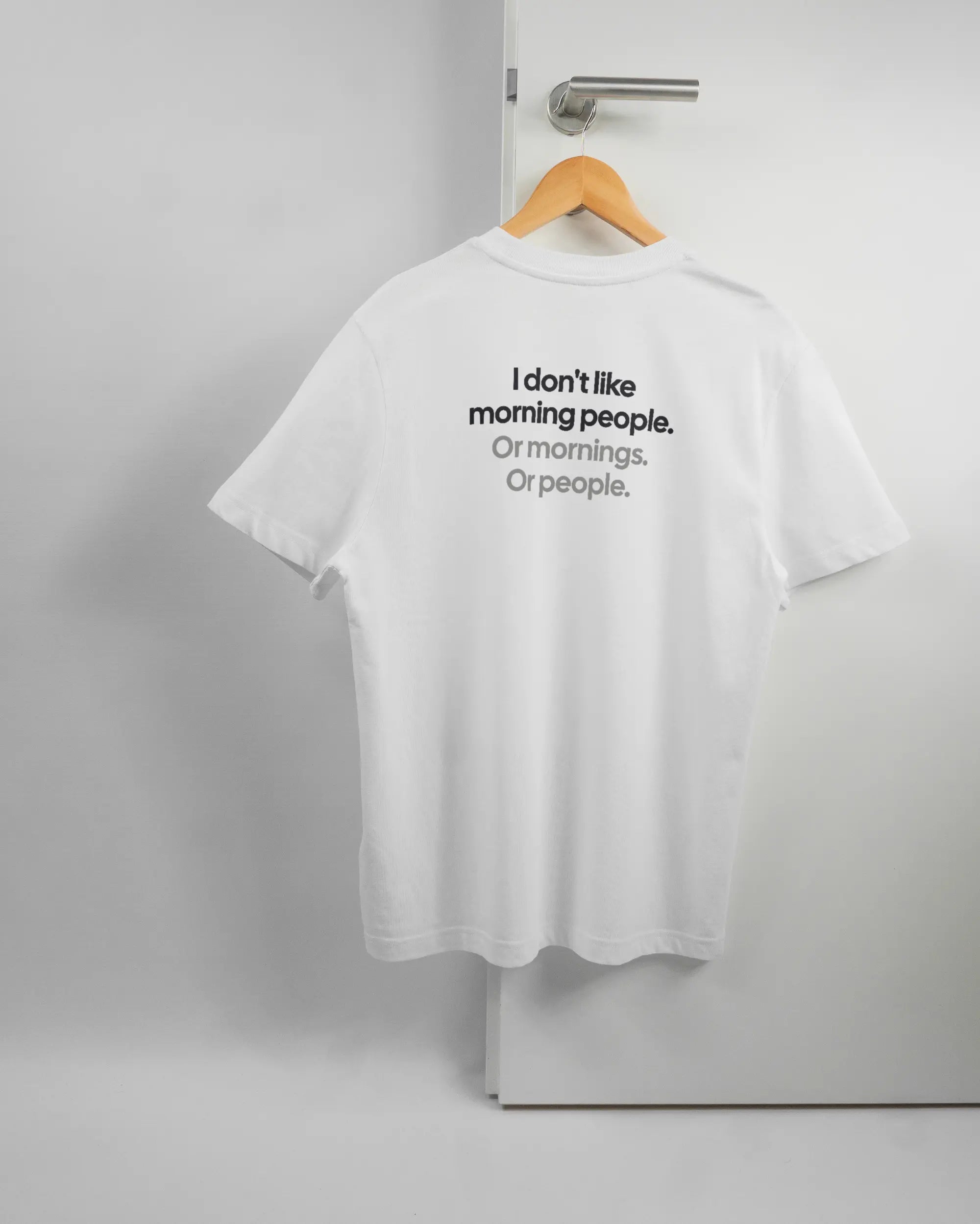 Rückseite des Organic Unisex T-Shirt Relaxed von Maondo mit dem Design Morning Person in der Farbe White und in der Größe S auf einem Bügel an der Türklinke aufgehängt