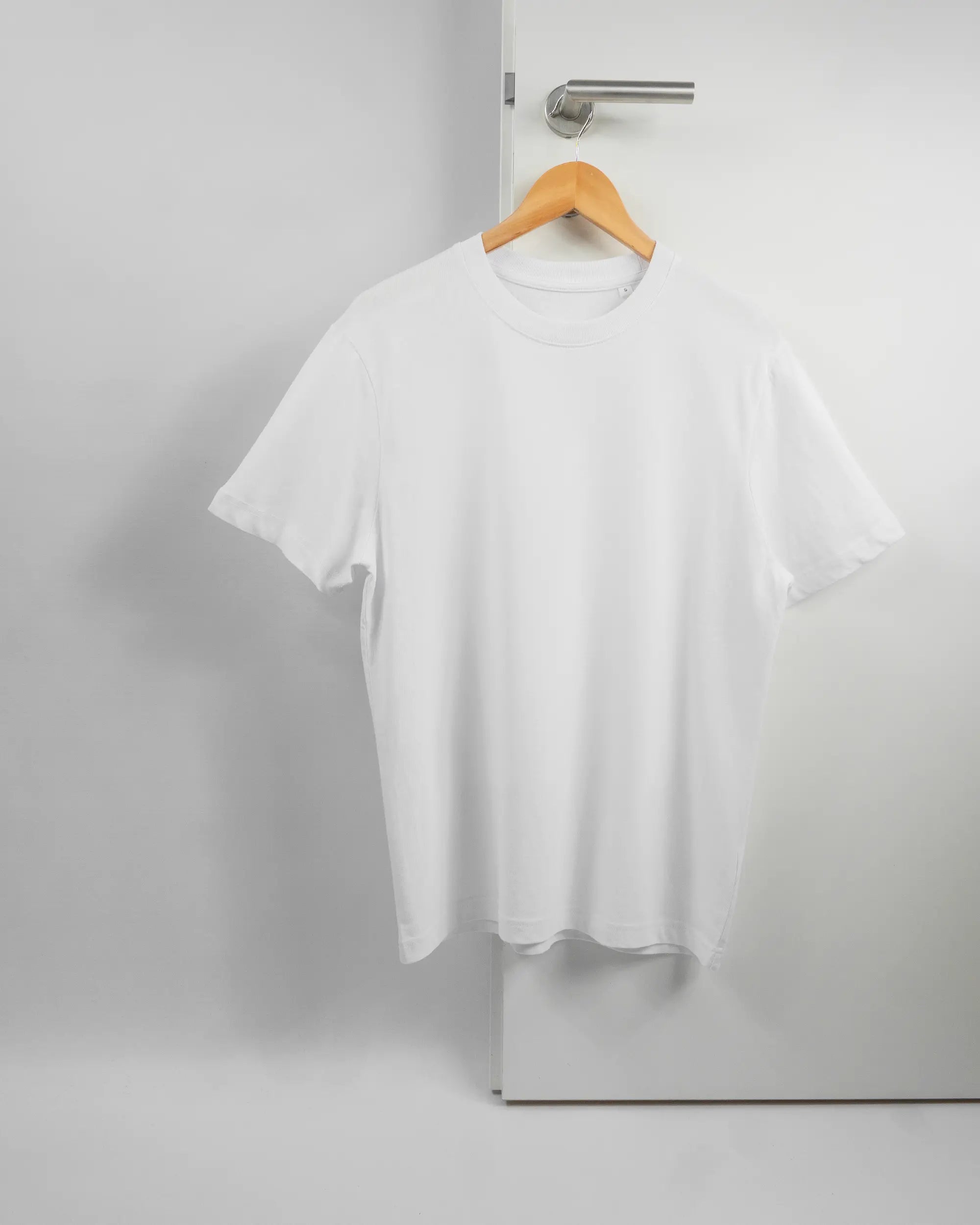 Vorderseite des Organic Unisex T-Shirt Relaxed von Maondo ohne Motiv in der Farbe White und in der Größe S auf einem Bügel an der Türklinke aufgehängt