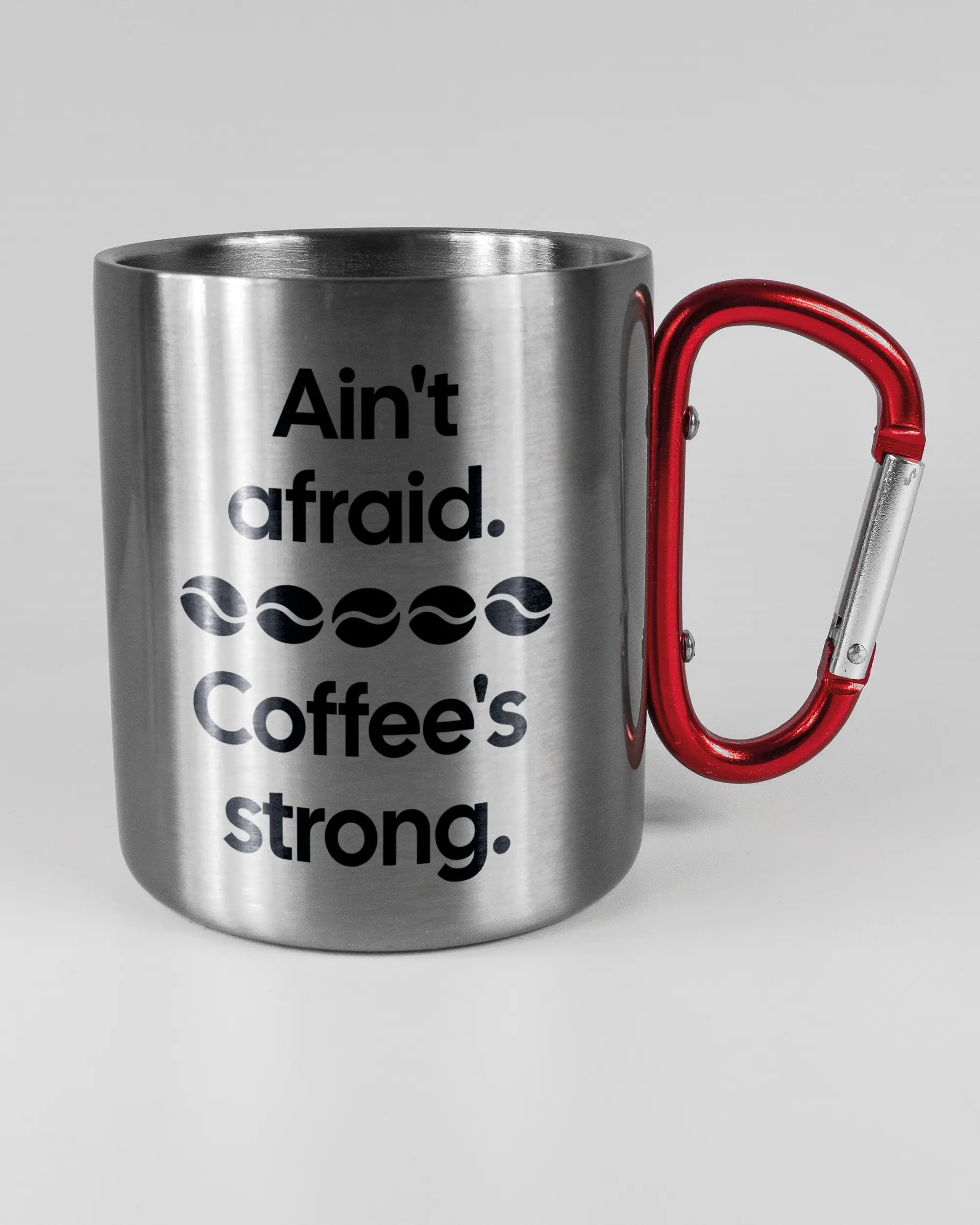 Alternativbild, das die rechte Seite der beidseitig bedruckten Edelstahltasse von Maondo mit dem Design Coffee is strong in der Farbe Metallic-Red auf einem Holztisch zeigt