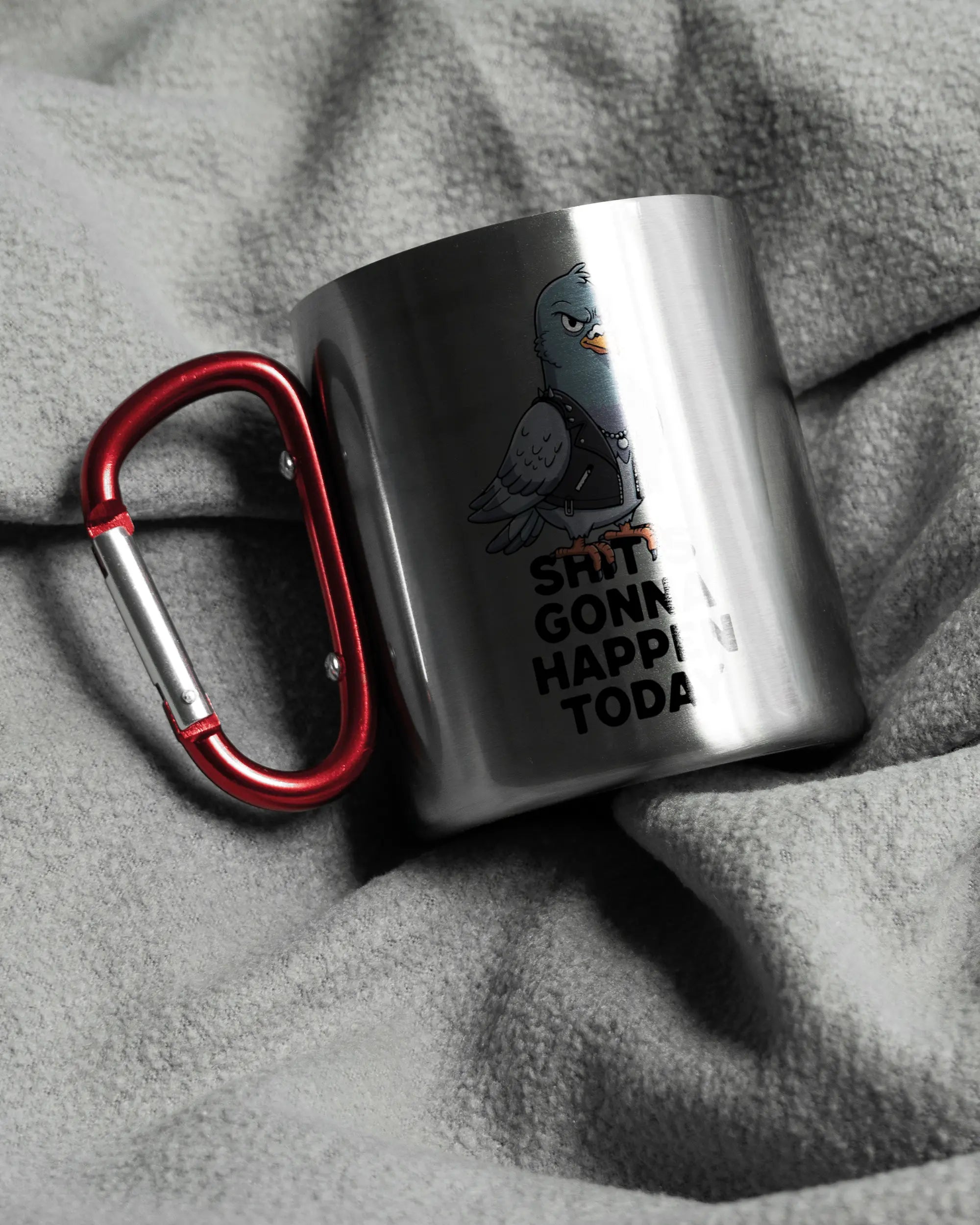 Aufnahme, die die linke Seite der beidseitig bedruckten Edelstahltasse von Maondo auf einer flauschigen Fließdecke mit dem Design Pigeon Pun in der Farbe Metallic-Red zeigt