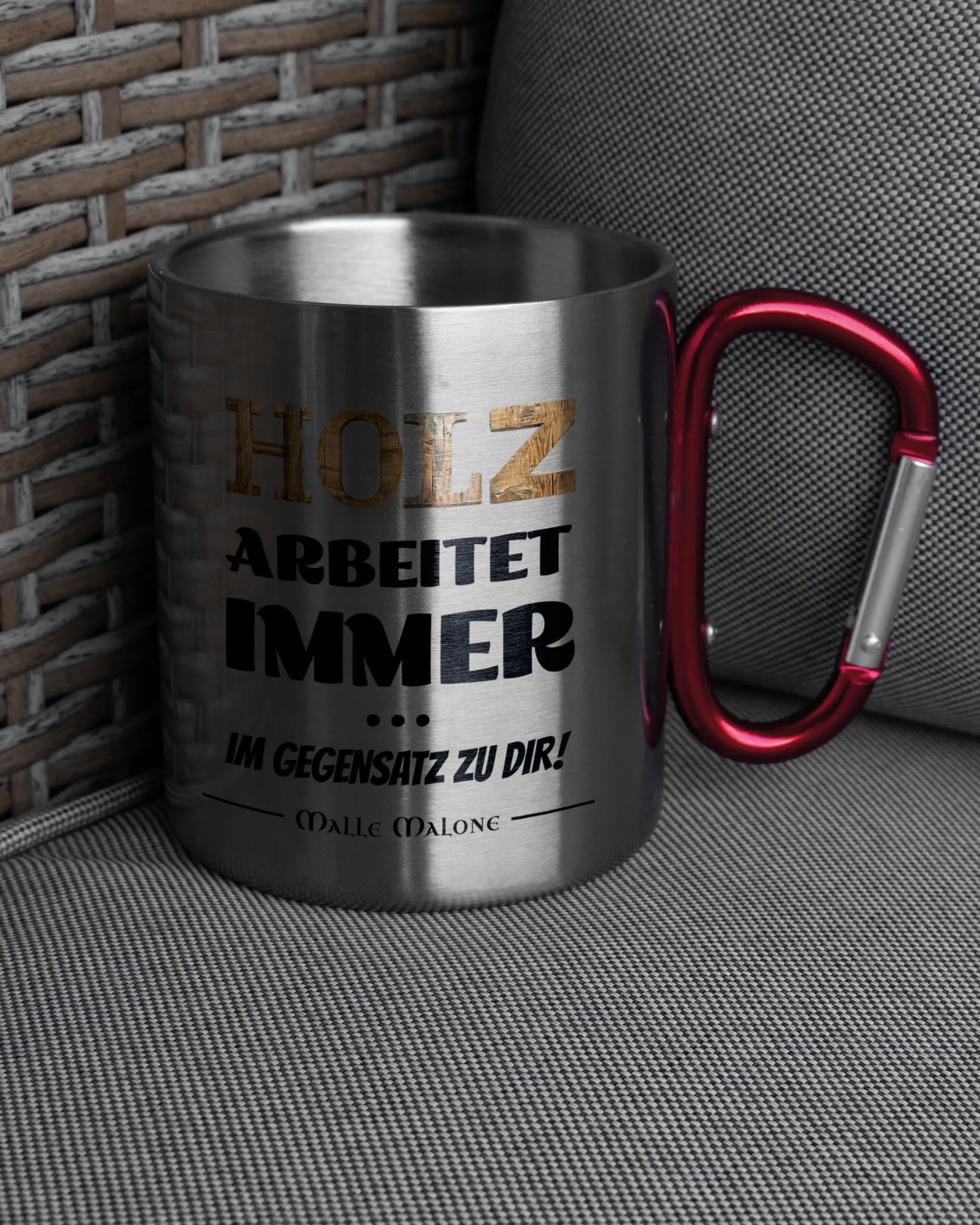Ansicht der rechten Seite der beidseitig bedruckten Edelstahltasse von Maondo auf einem Balkonmöbel bzw. Campingstuhl mit dem Design Holzarbeit in der Farbe Metallic-Red